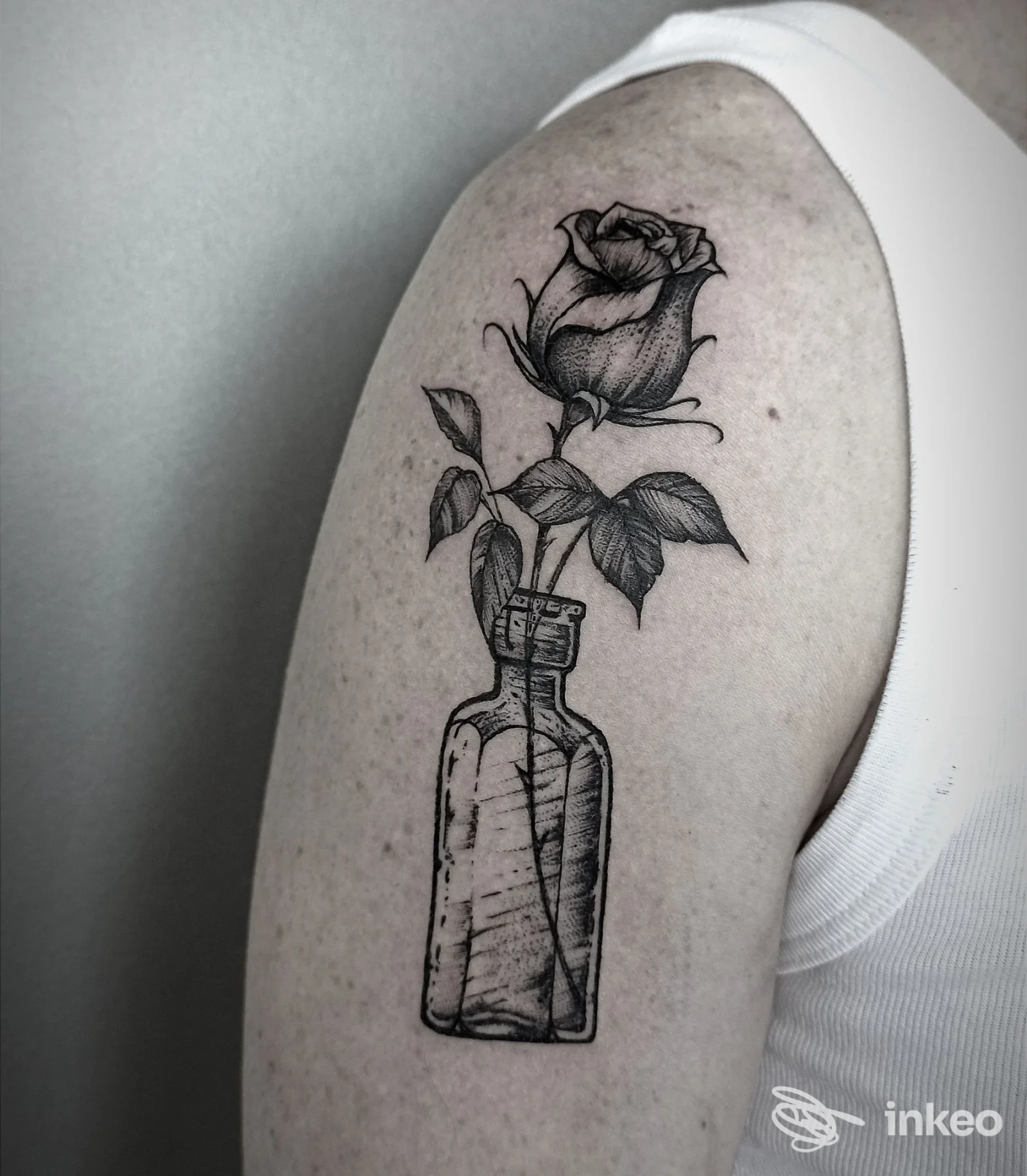 Rosa tatuata con dettagli incisione che nasce da una bottiglia sul deltoide, foto di DELIRIO TATTOO AND GALLERY a Camisano Vicentino.