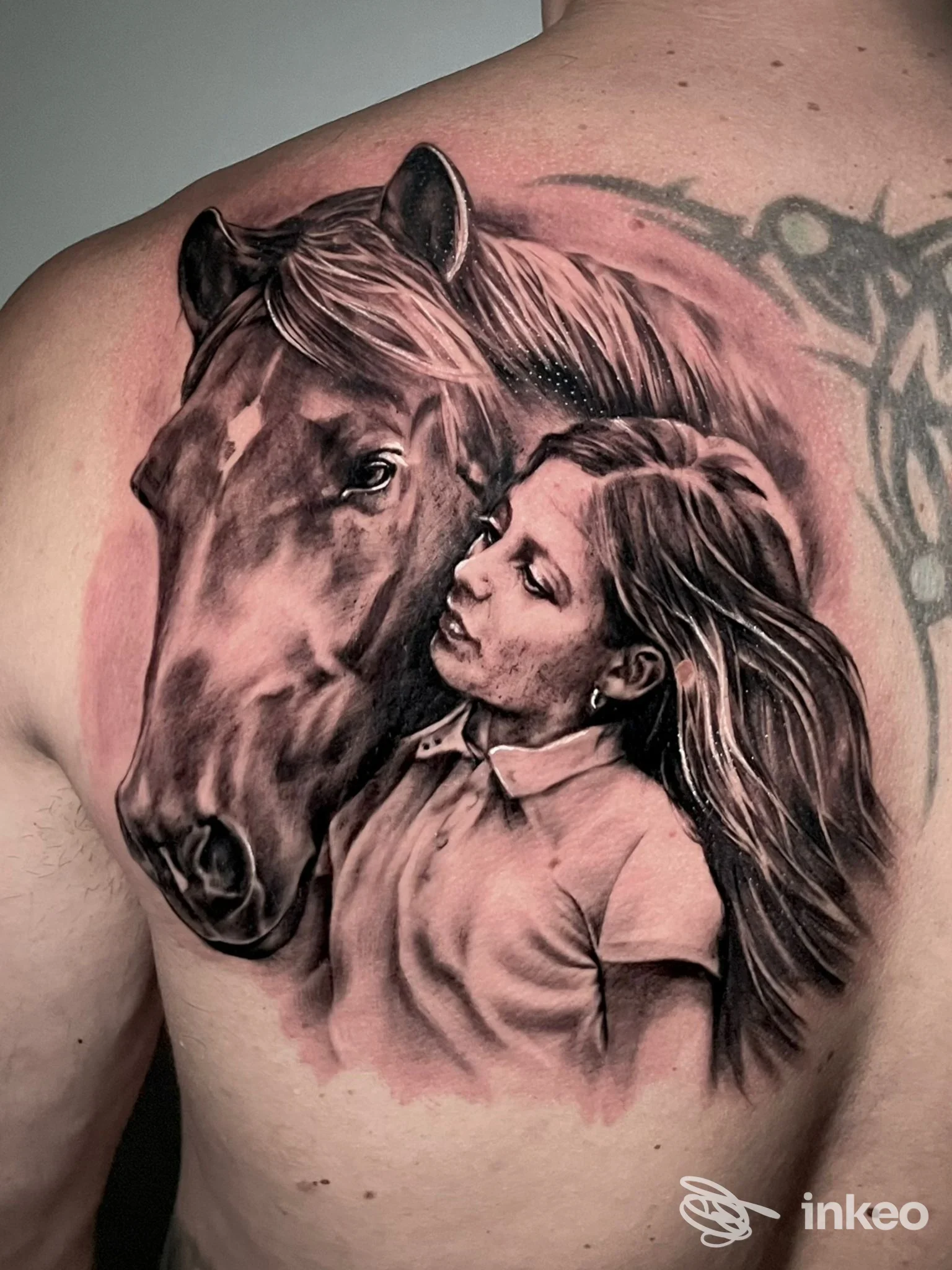 Tatuaggio realistico di un cavallo e il volto di una bambina sulla parte alta della schiena. Dark Alley Tattoo Studio, Zevio.