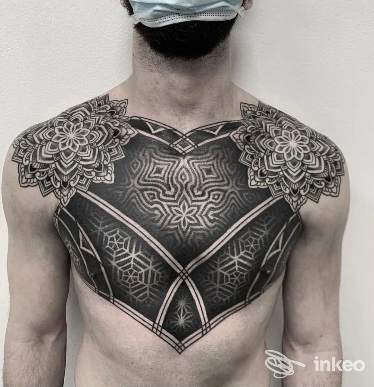 Ampio tatuaggio geometrico e ornamentale sul petto e spalle di un uomo, foto fornita da Dark Mind Tattoo Studio, Meledo.
