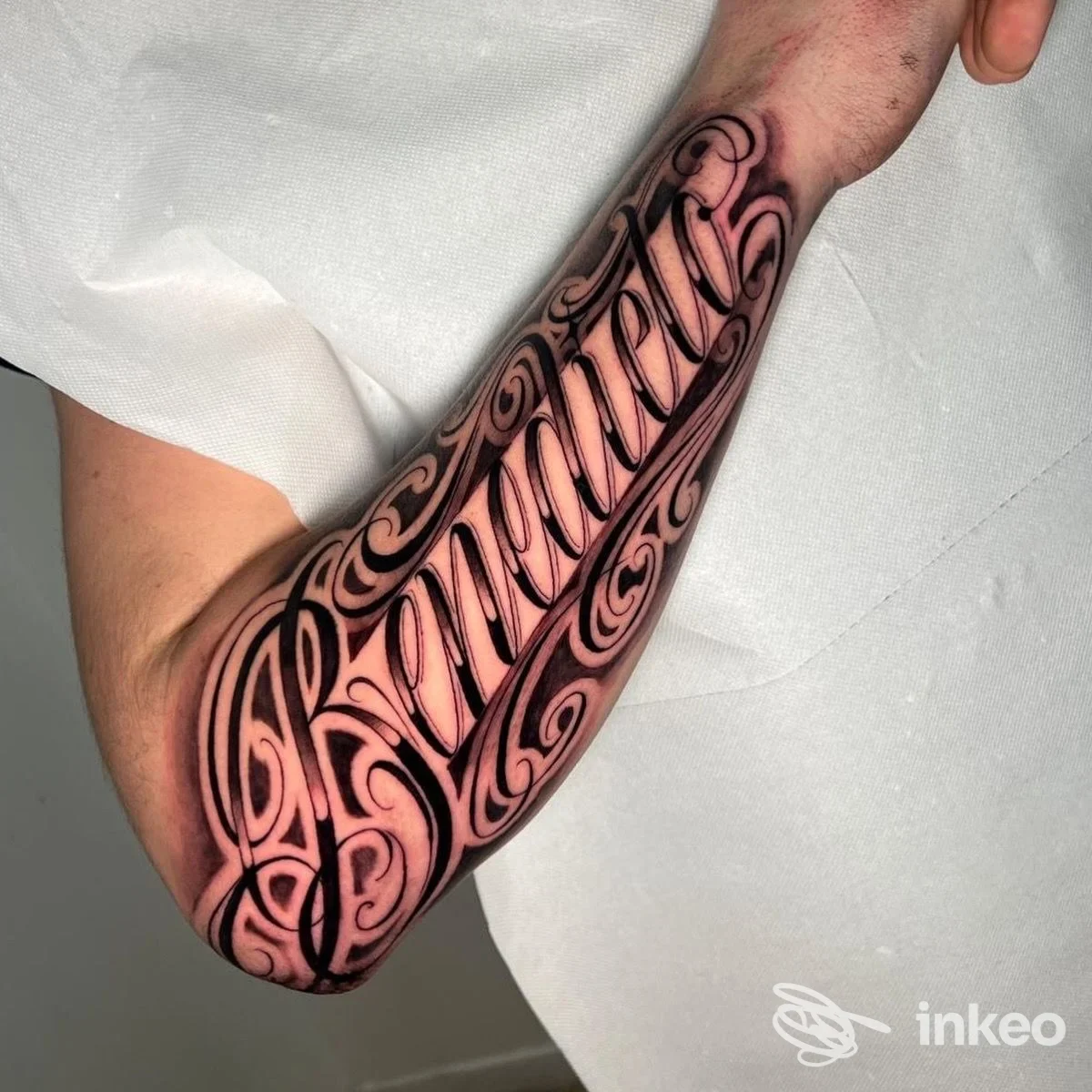 Ampio tatuaggio lettering nero sull'avambraccio, pelle leggermente arrossata dopo la sessione - Emink Tattoo Studio, Vicenza.