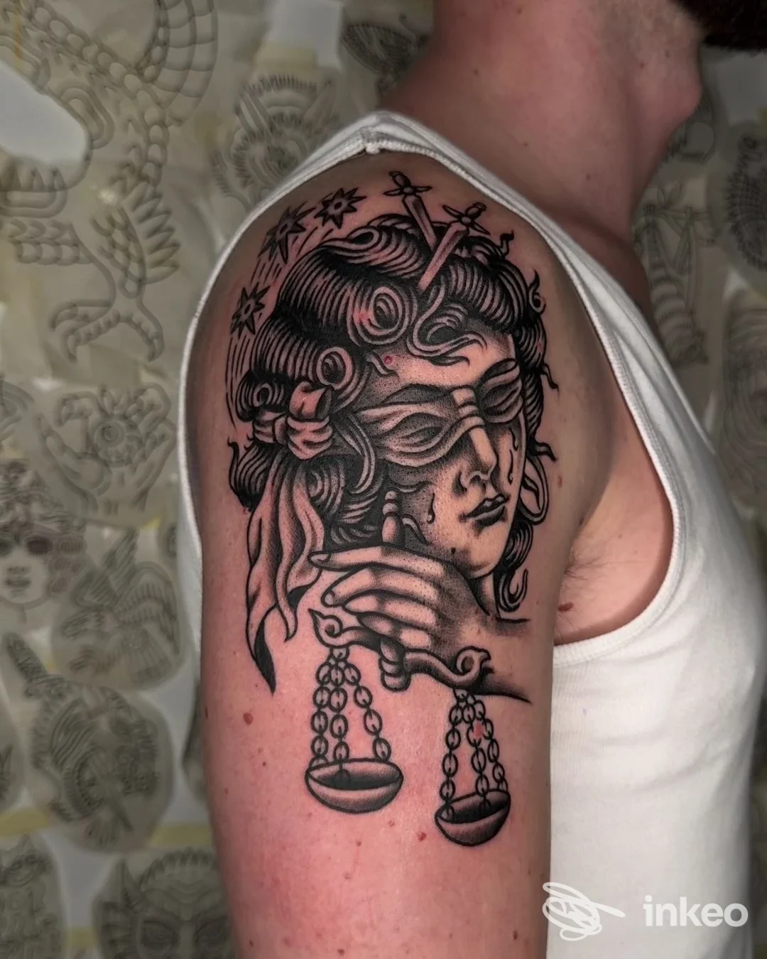 Tatuaggio a inchiostro nero di una donna bendata con bilancia sulla spalla, Emink Tattoo Studio, Vicenza.