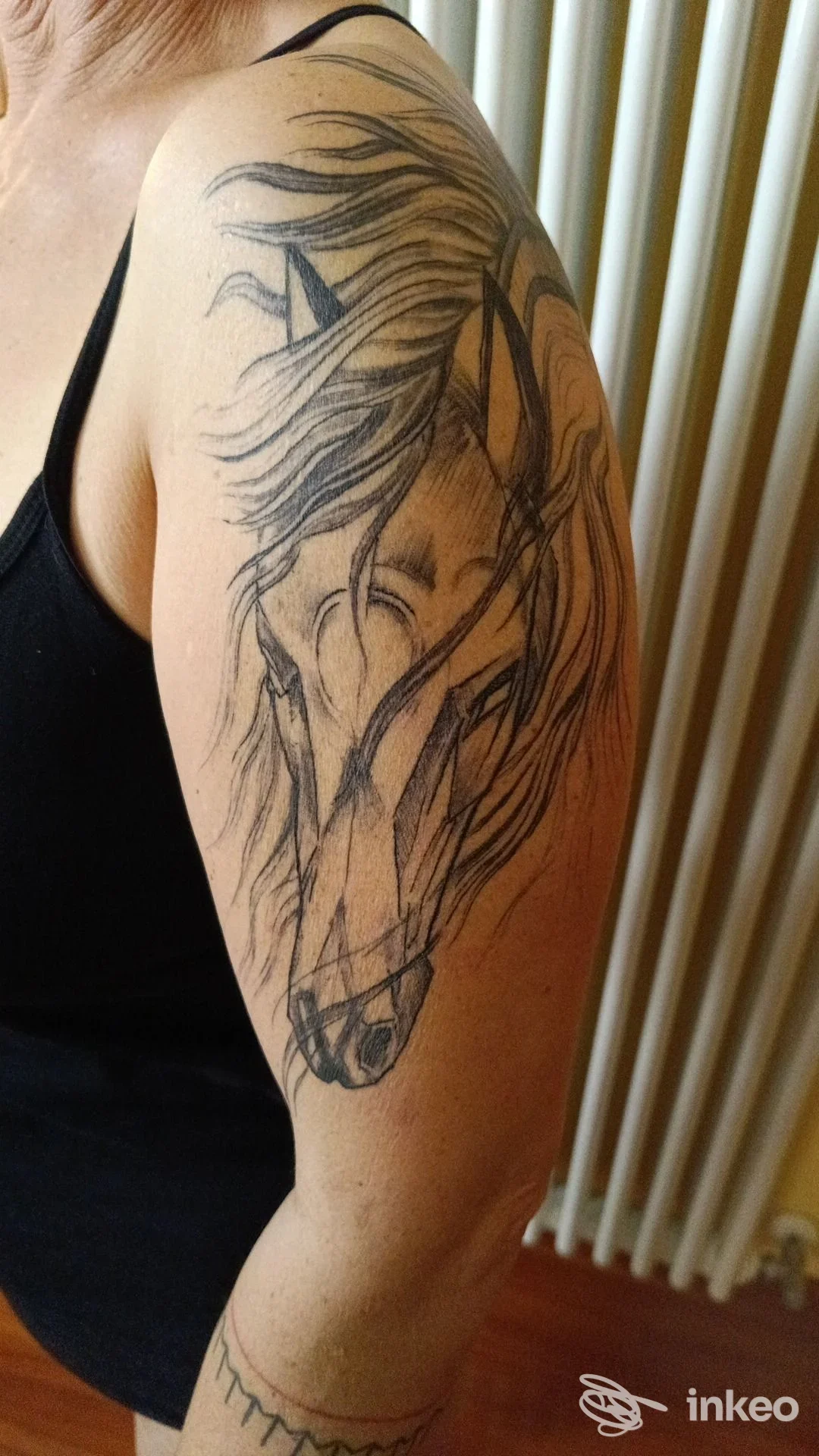 Tatuaggio a inchiostro nero di una testa di cavallo su spalla e braccio superiore, foto fornita da Fiumix & Quila Tattoo, Cittadella.