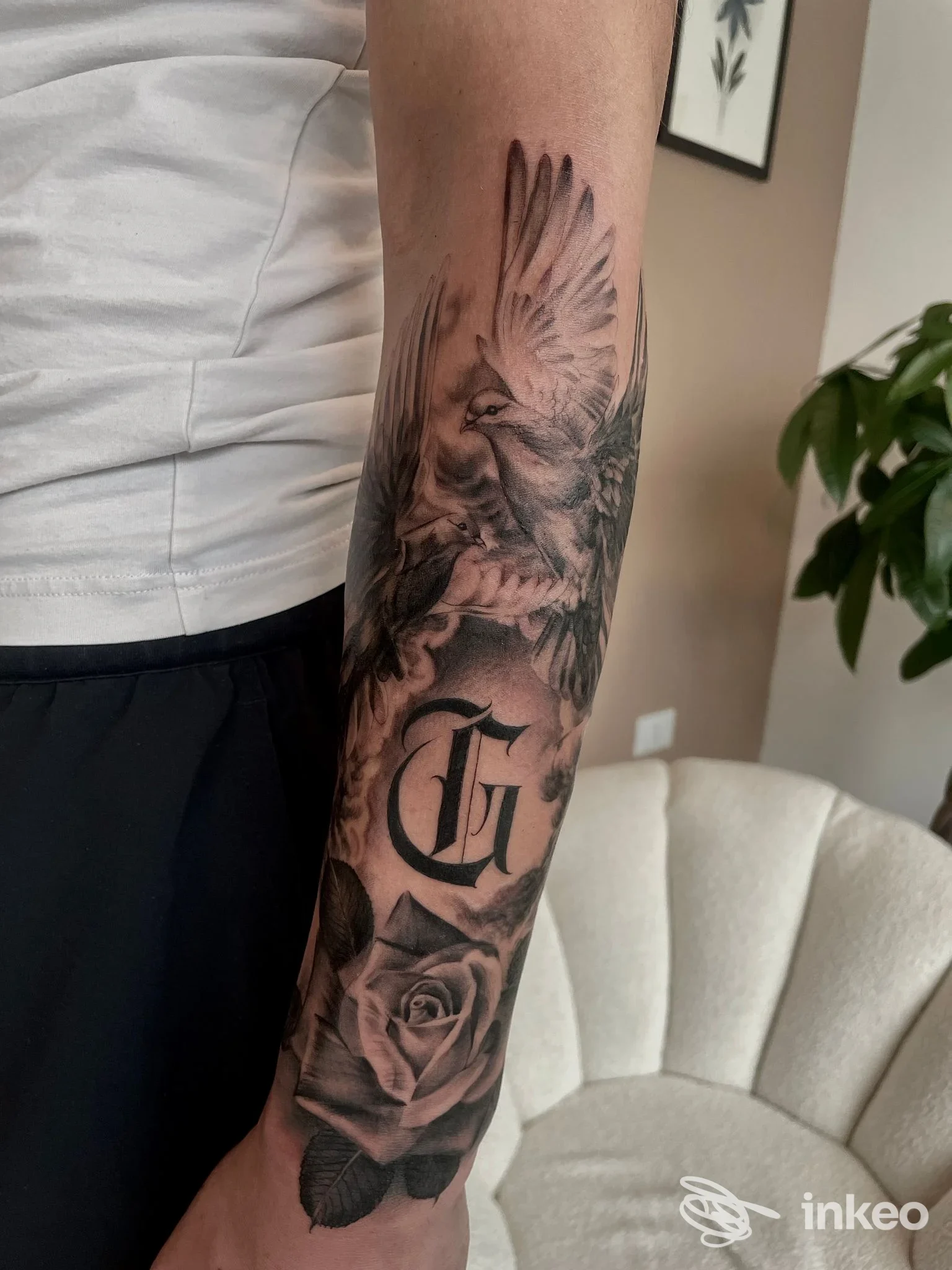 Avambraccio tatuato realistico con colomba, rosa e lettera gotica, foto fornita da HandMade Tattoo Lab, Este.