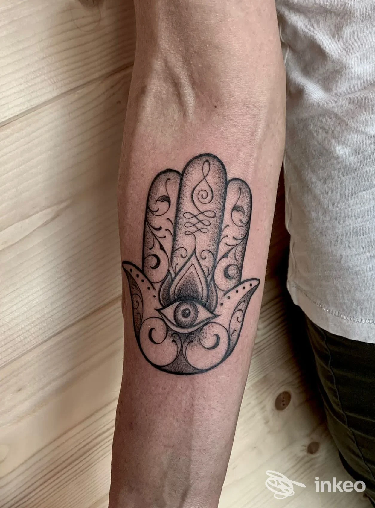 Tatuaggio Hamsa nero con occhio centrale sull'avambraccio, eseguito da Gamma Line Tattoo & Piercing a Sedico.