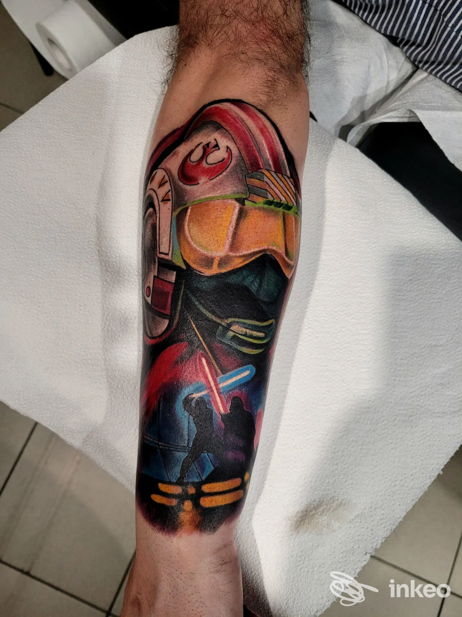 Tatuaggio a colori su avambraccio con elmo e figure, foto fornita da Hostile Tattoo Studio, Feltre.