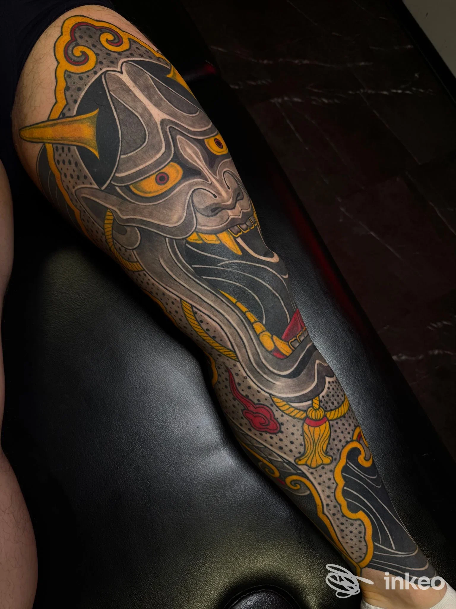 Tatuaggio a manica completa su braccio con motivo a maschera stilizzata in nero, grigio, giallo e rosso — Humandroid Tattoo Studio, Silea.