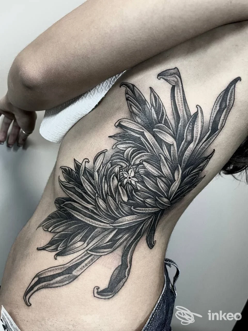 Ampio tatuaggio floreale in bianco e nero che copre il fianco di una persona, fotografato per Humandroid Tattoo Studio, Silea.