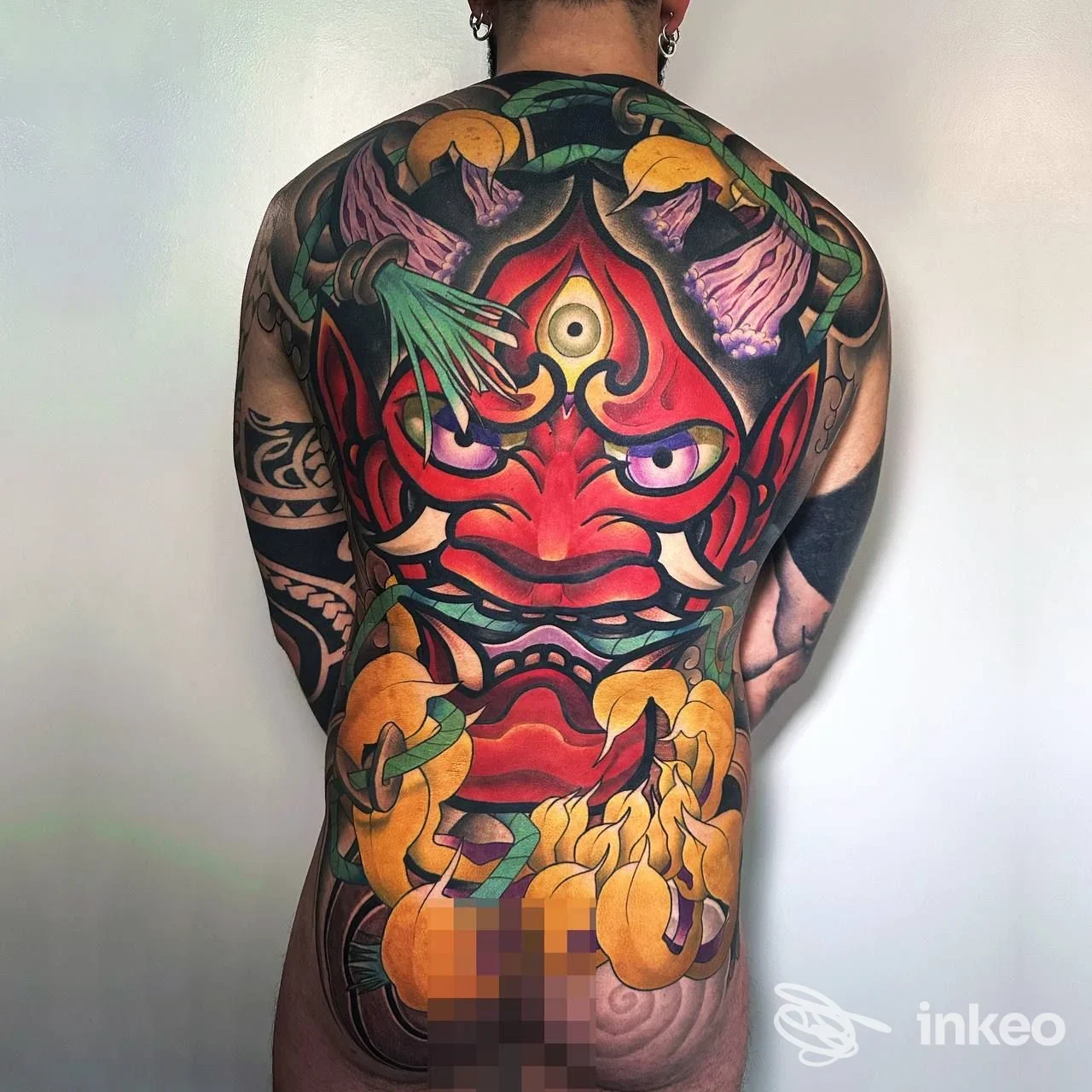 Ampia schiena tatuata a colori con motivo centrale rosso, foto proveniente da Humandroid Tattoo Studio, Silea.