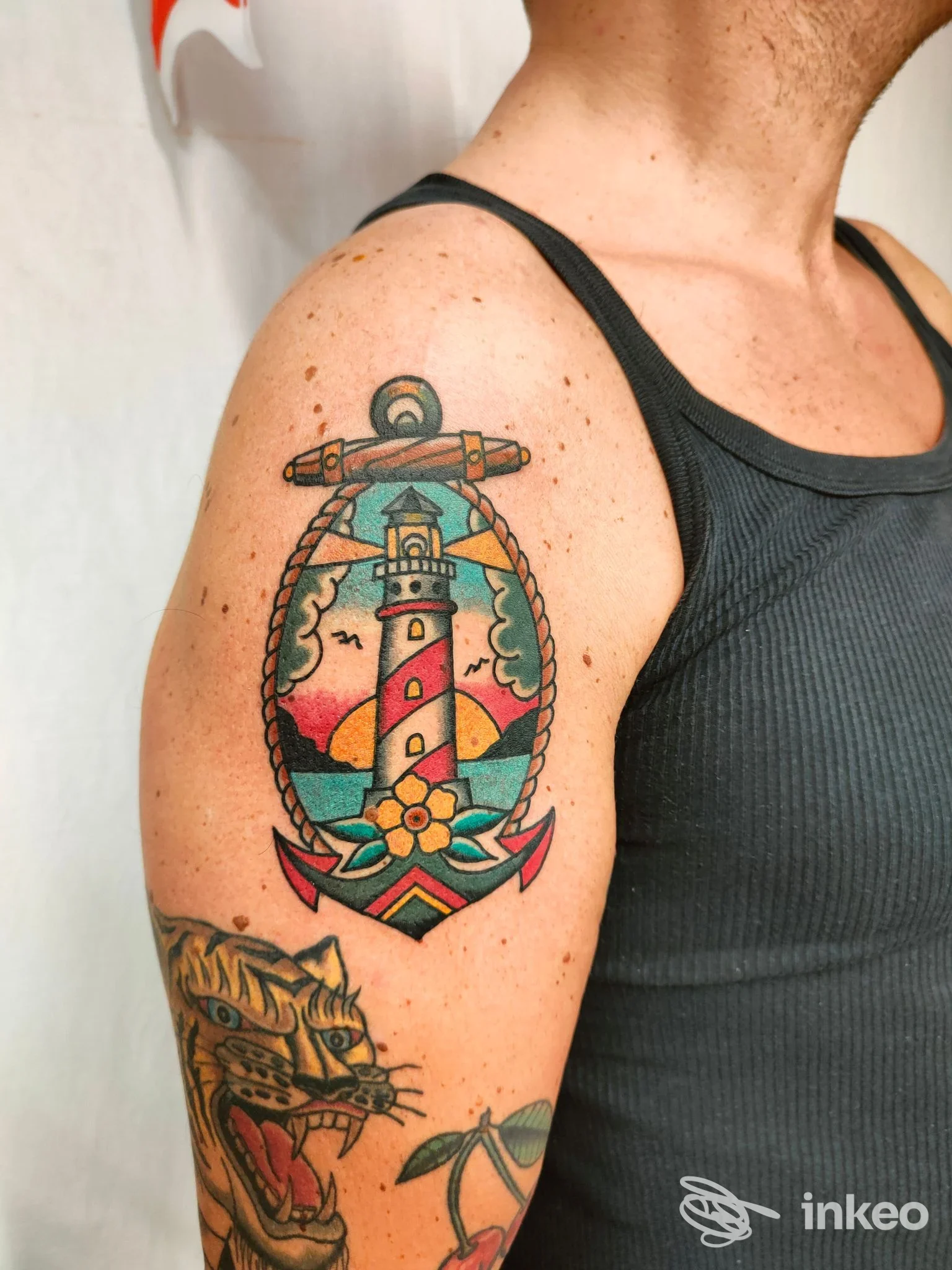 Tatuaggio tradizionale con faro e ancora sul deltoide, foto inviata da INKAE TATTOO, Venezia.