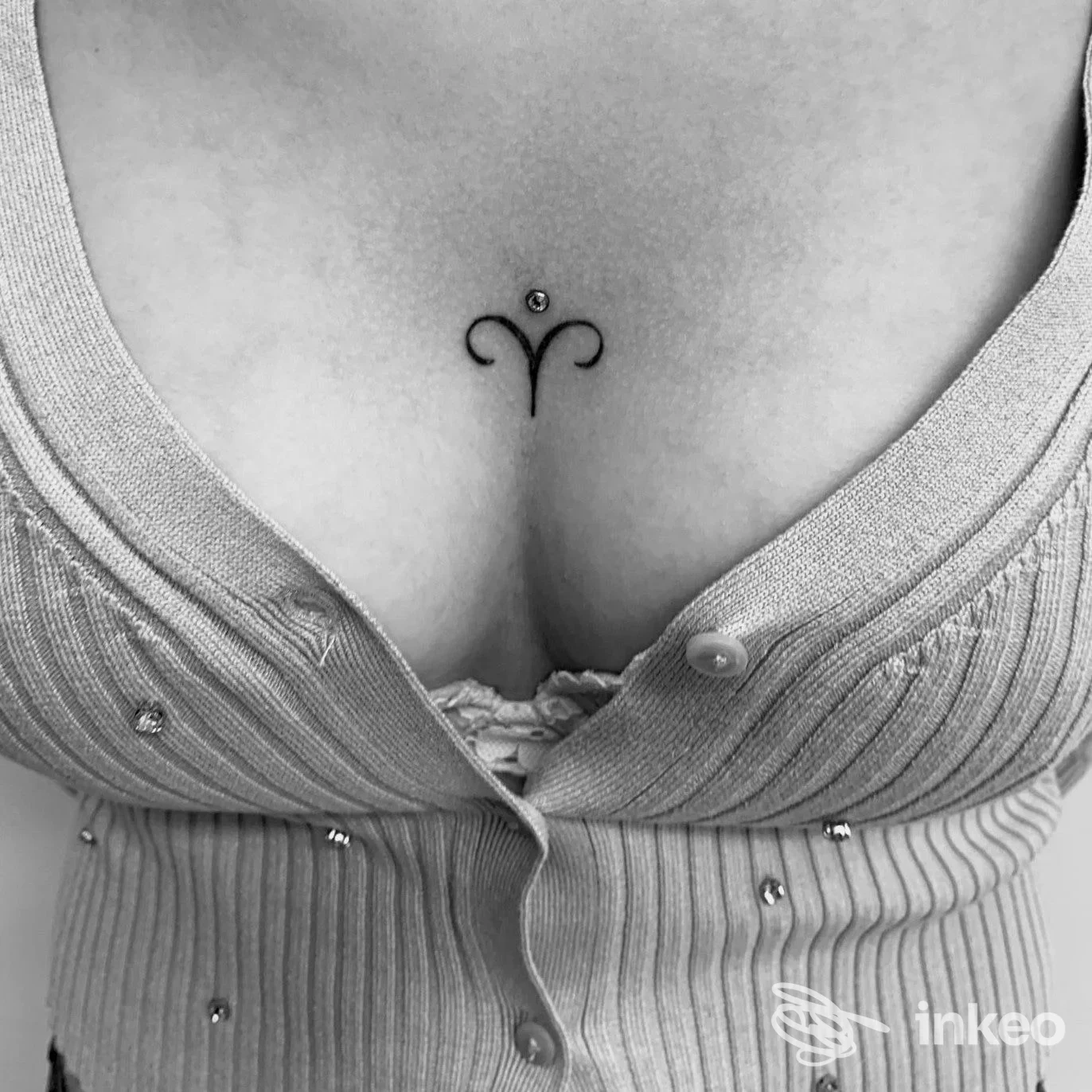Piccolo tatuaggio minimale in nero centrato sullo sterno, fotografato su pelle reale — Il Cervello Anarchico Tattoo, Bassano del Grappa.