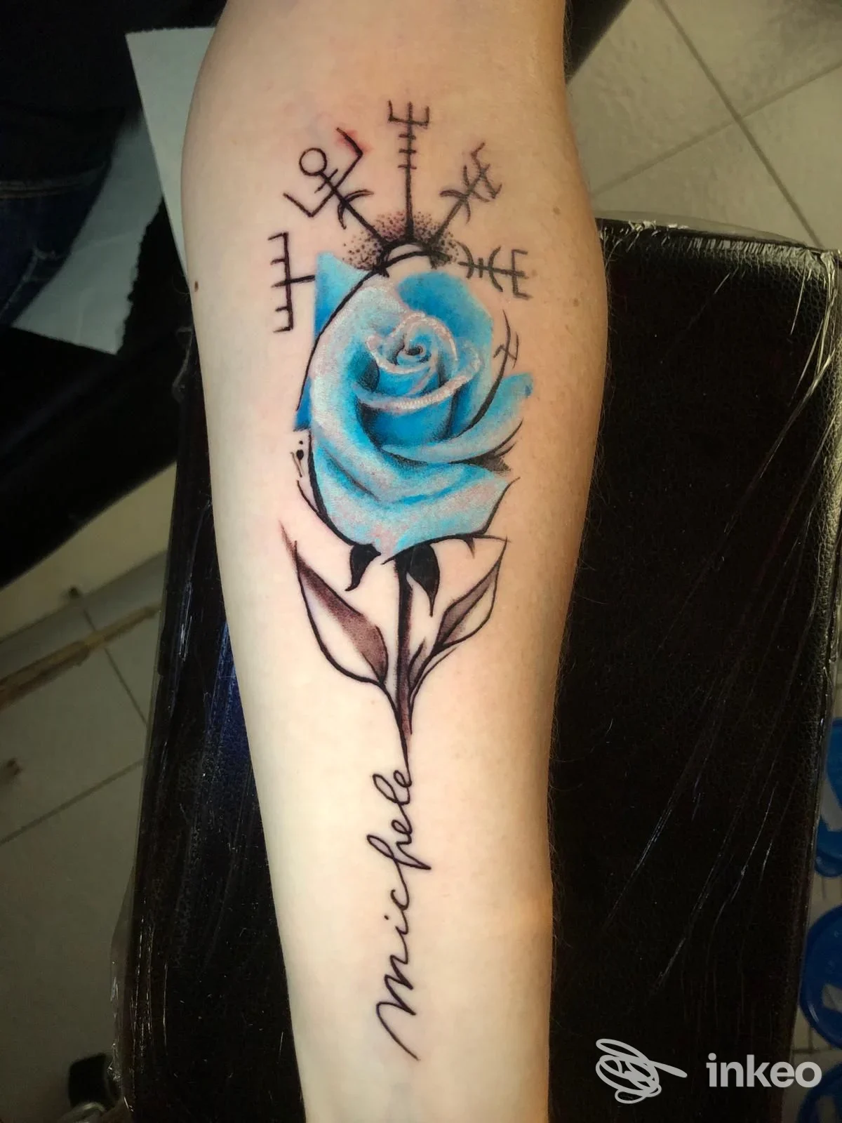 Tatuaggio di una rosa azzurra con gambo stilizzato e la firma 'michele' sull'avambraccio, IV DIMENSIONE Tattoo Studio, Treviso.
