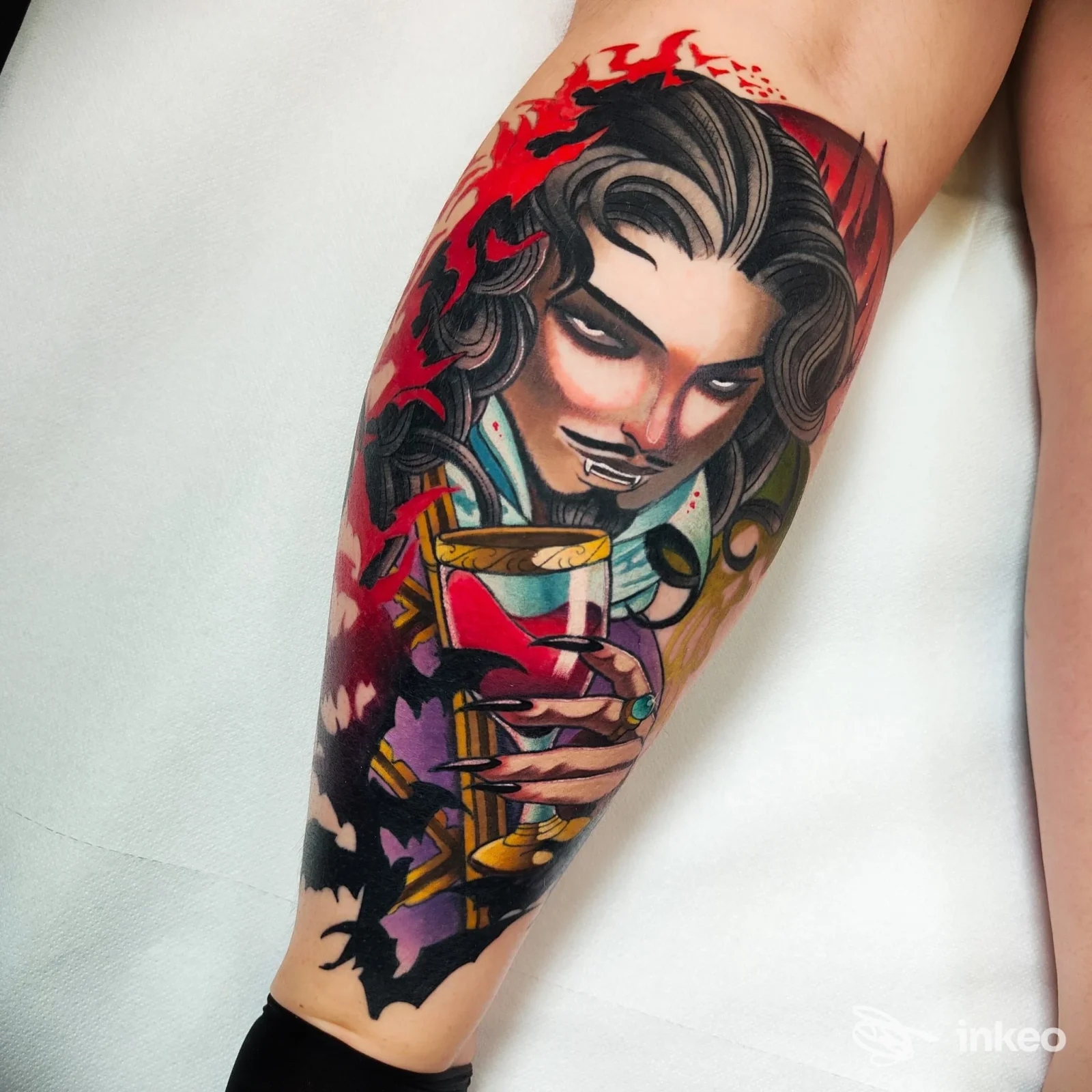 Tatuaggio colorato su polpaccio con volto stilizzato che regge una coppa, realizzato da IV DIMENSIONE Tattoo Studio a Treviso.