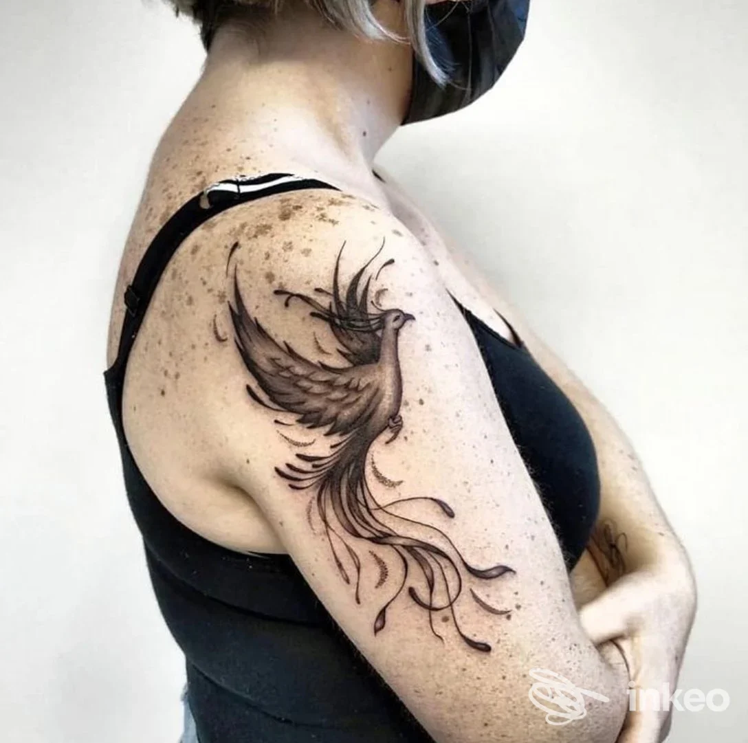 Tatuaggio a inchiostro nero a forma di uccello sul braccio superiore, foto dello studio Kamatattoo a Stra.