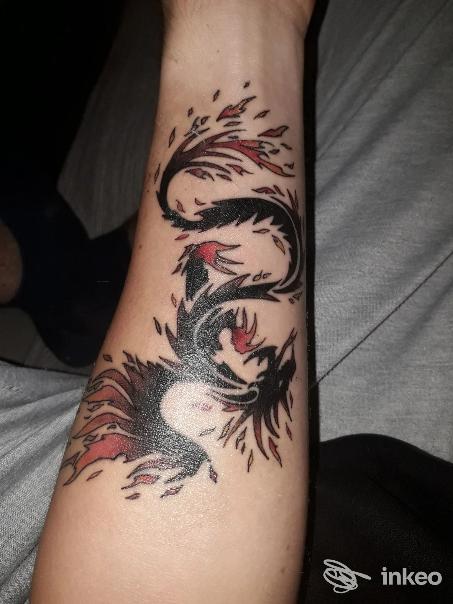 Tatuaggio stilizzato nero e rosso su avambraccio, foto inviata da Kamatattoo a Stra.