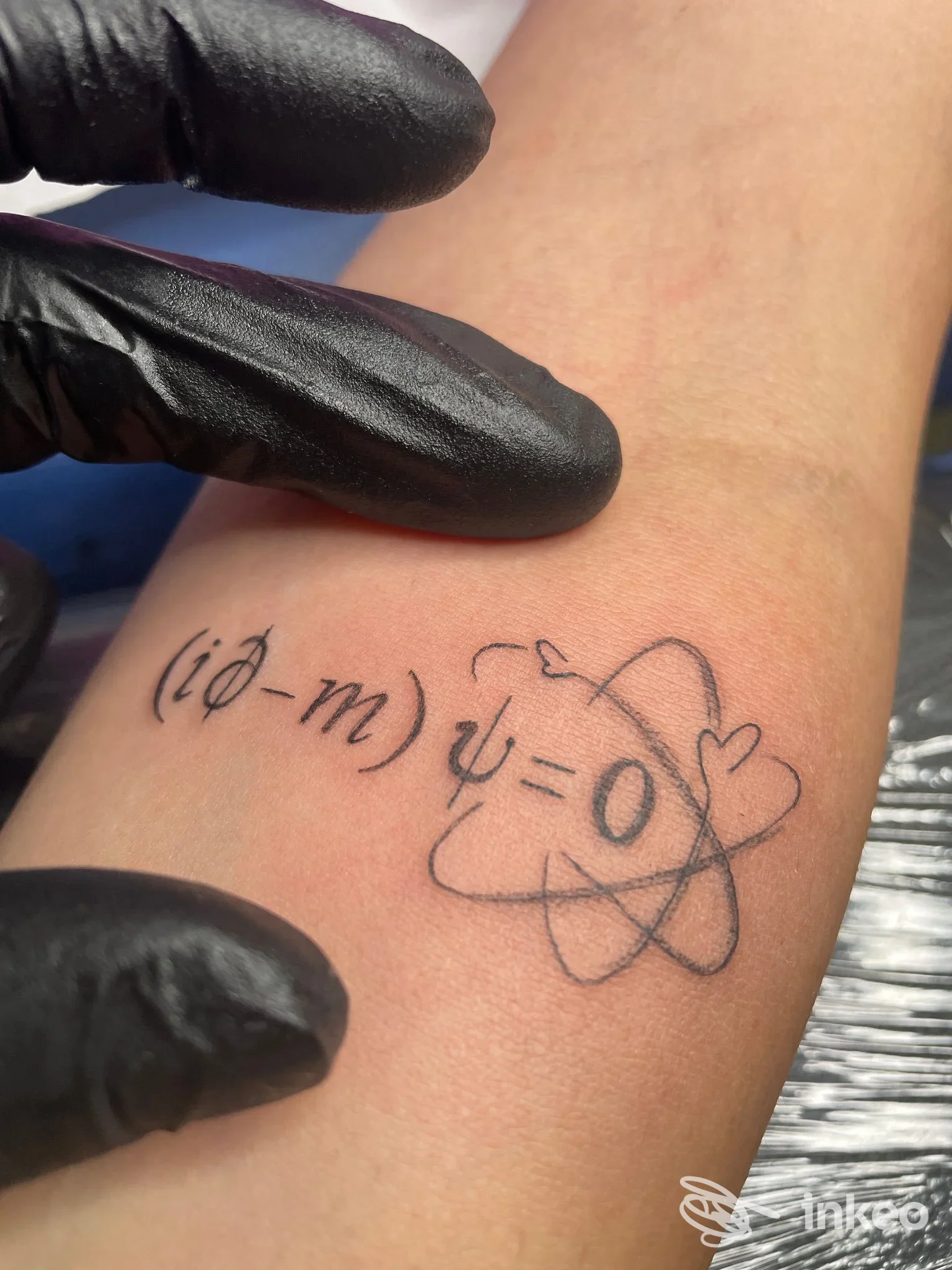 Primo piano di un tatuaggio linework con formula e simbolo atomico sul avambraccio, realizzato da LISA MARY ZONTA TATTOO, Bassano del Grappa.