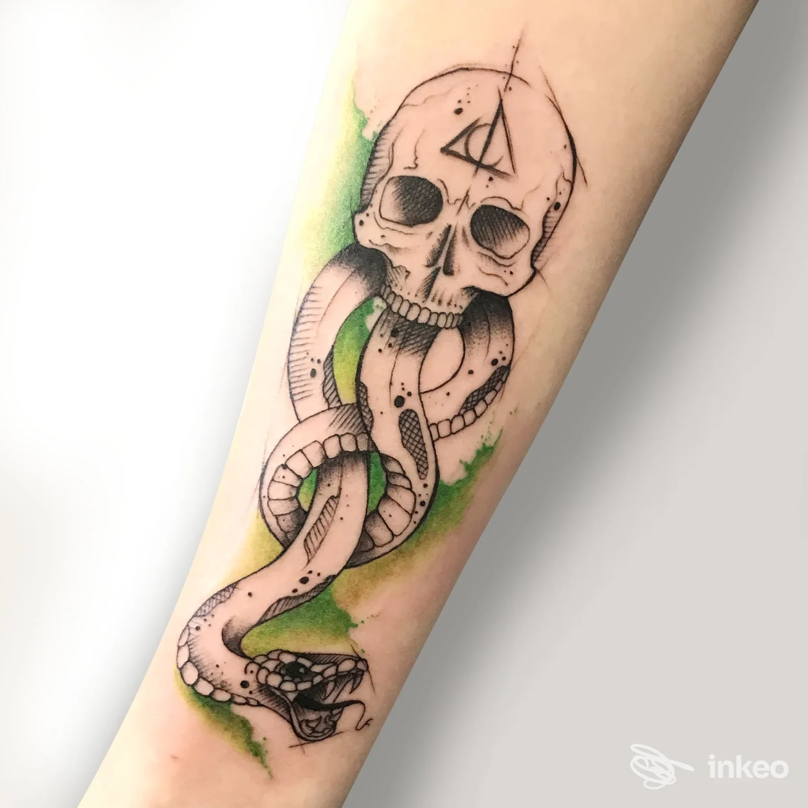 Tatuaggio su avambraccio con teschio e serpente avvolto, dettagli linework e tocchi verdi – LaPerfida Bottega Tattoo Studio, Vittorio Veneto.