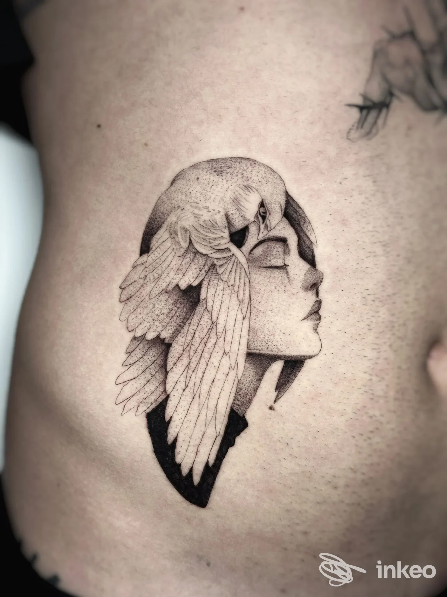 Tatuaggio in bianco e nero al fianco: volto femminile stilizzato con ali, LV Tattoo Studio, Montecchio Maggiore.