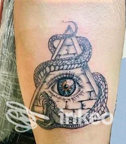 Tatuaggio su avambraccio con occhio realistico dentro una piramide di mattoni e serpente avvolto — Luci ed Ombre Ink Tattoo Studio, Motta di Livenza