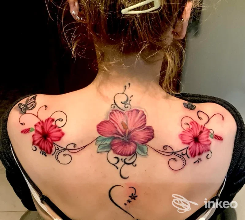 Foto della parte superiore della schiena con tre fiori tatuati in rosa e elementi ornamentali, scattata per Luci ed Ombre Ink Tattoo Studio, Motta di Livenza.