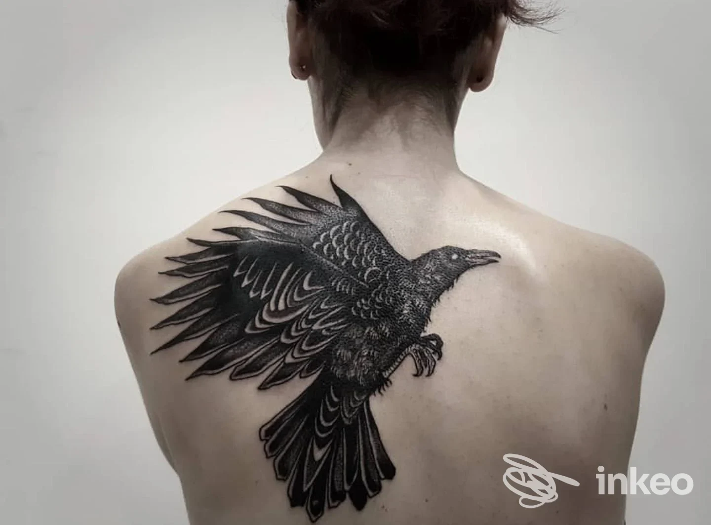 Grande tatuaggio di corvo nero sulla parte superiore della schiena, fotografato per Nord Tattooing a Belluno.