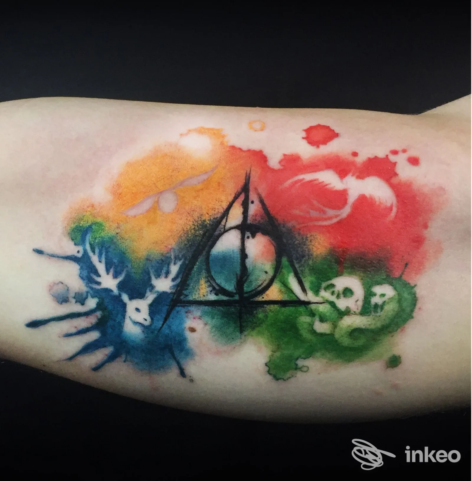 Tatuaggio acquerello su avambraccio, con simbolo centrale e macchie colorate — Octopus Ink Tattoo Studio, Padova.