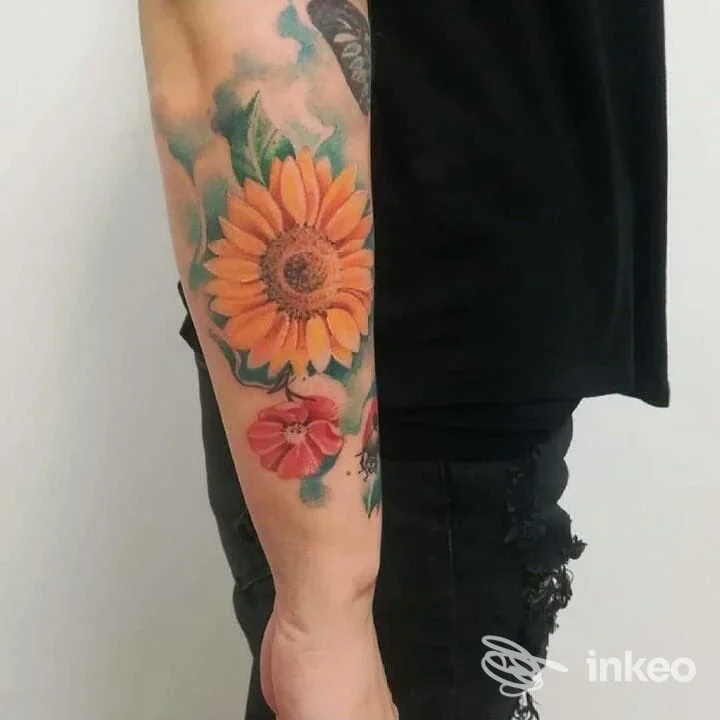 Avambraccio tatuato con un girasole giallo e fiori colorati, fotografia del lavoro condivisa da Materia Tattoo Lab a Creazzo.
