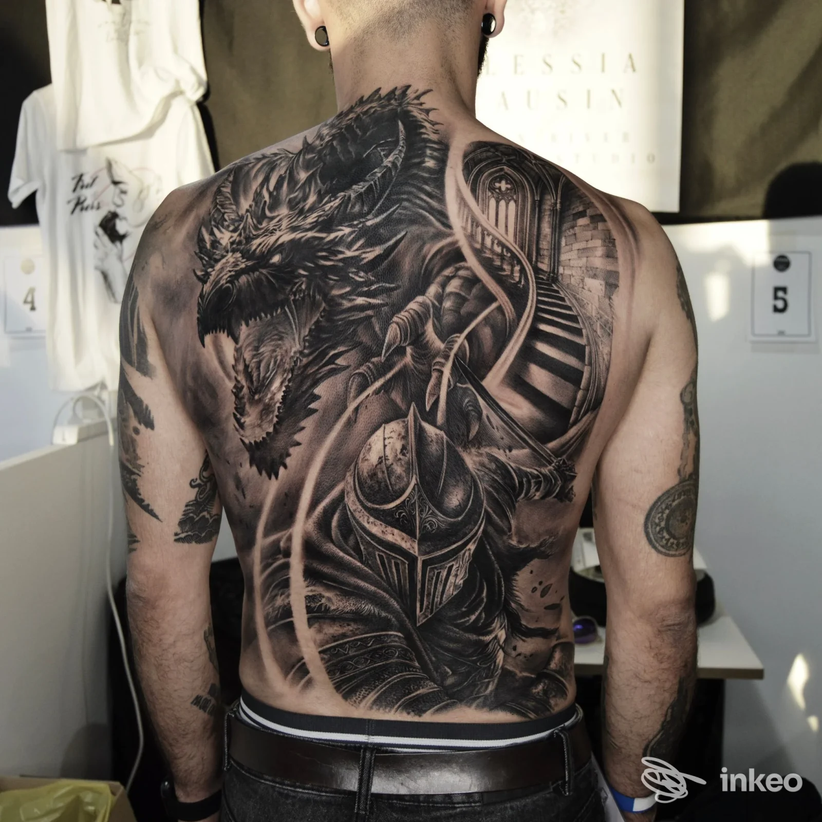 Ampia schiena tatuata in bianco e nero con drago e cavaliere, foto di Moon River Tattoo Studio a Robegano che mostra il lavoro sul cliente.