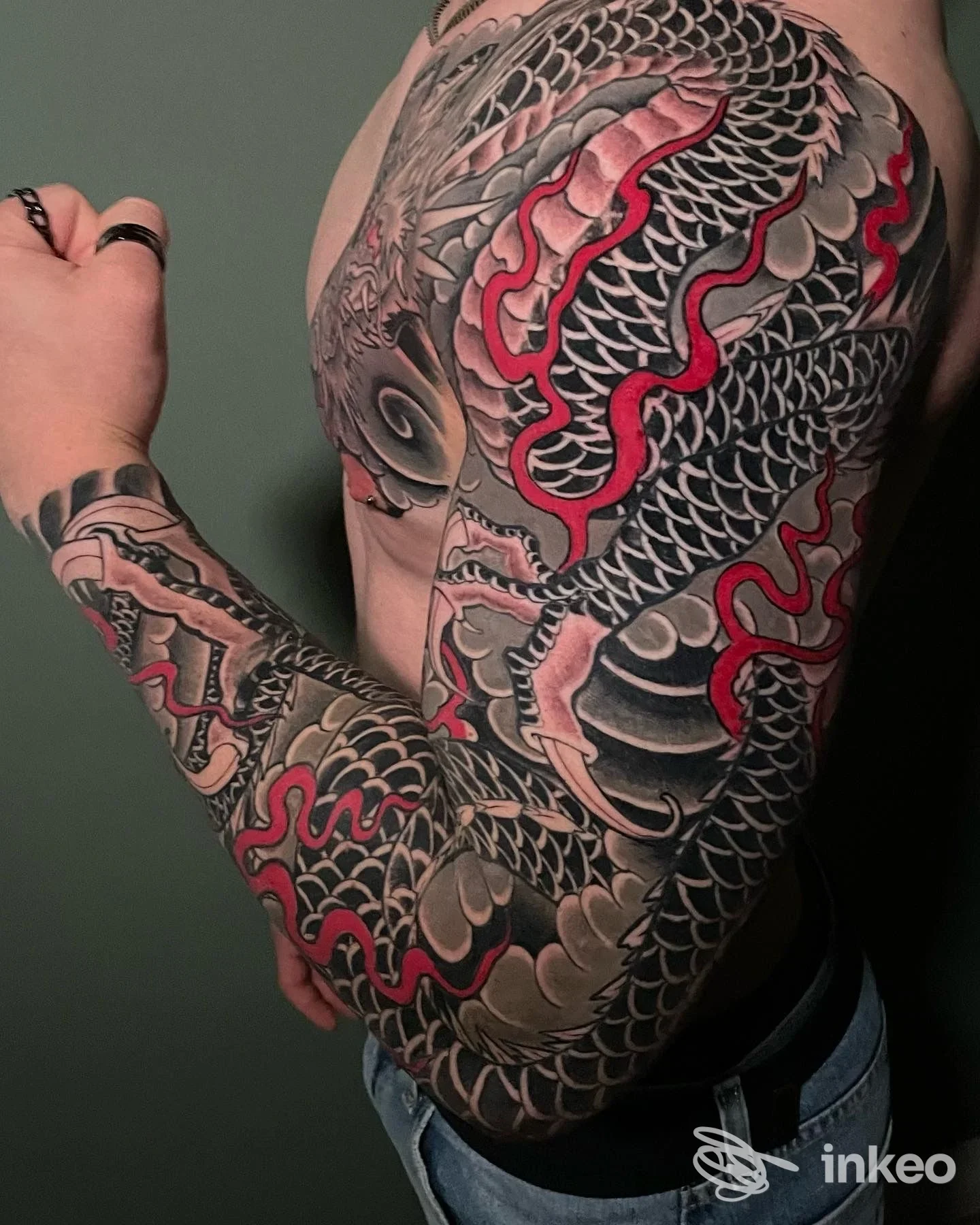 Manica tatuata dettagliata su braccio e spalla, fotografia per Original Sin Tattoo Shop a Nogara, mostra scaglie nere e accenti rossi.