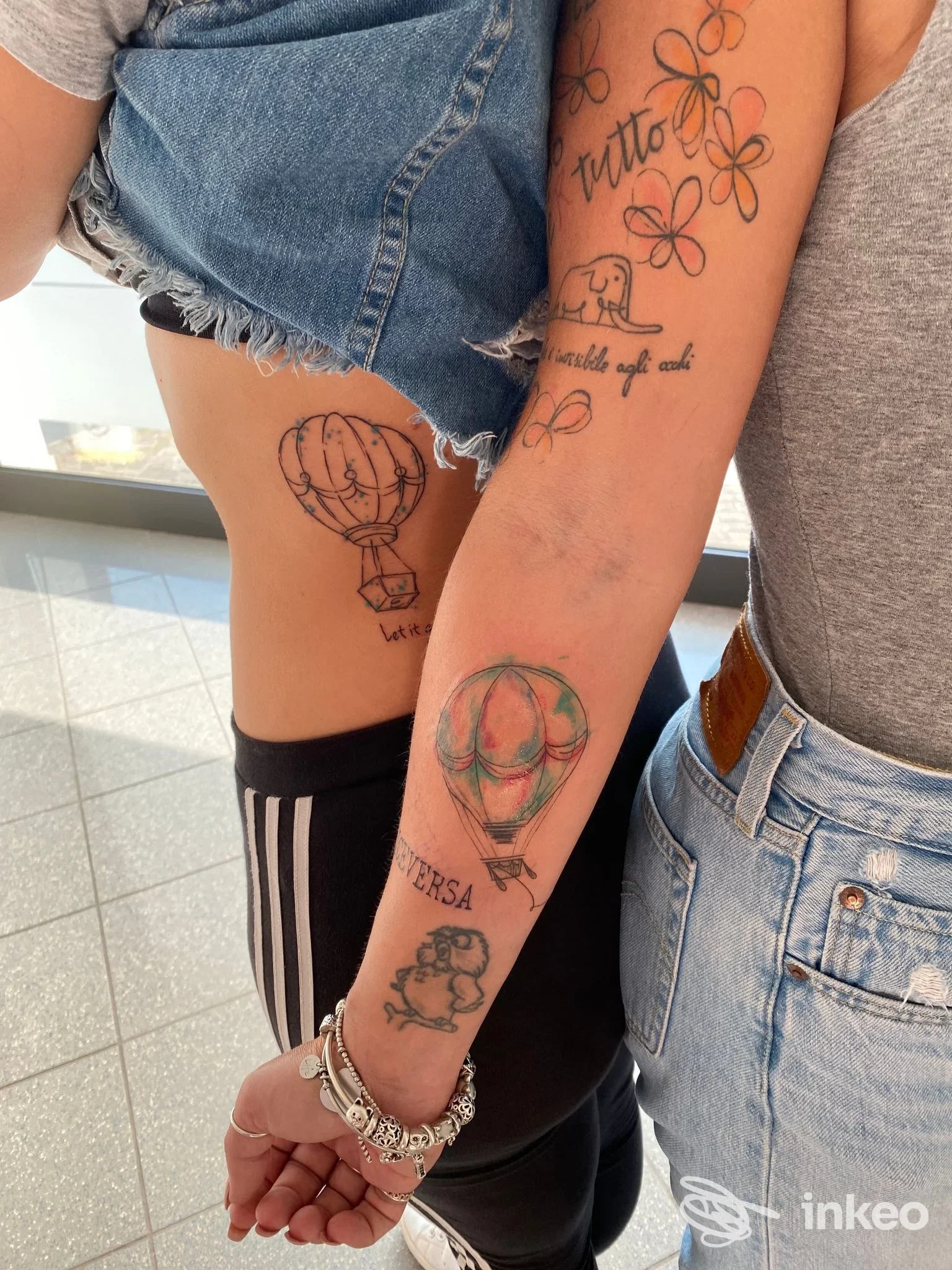 Dettaglio di tatuaggi su avambraccio e fianco con mongolfiere, fiori ed elefante — Owl Tattoo studio, Malo.