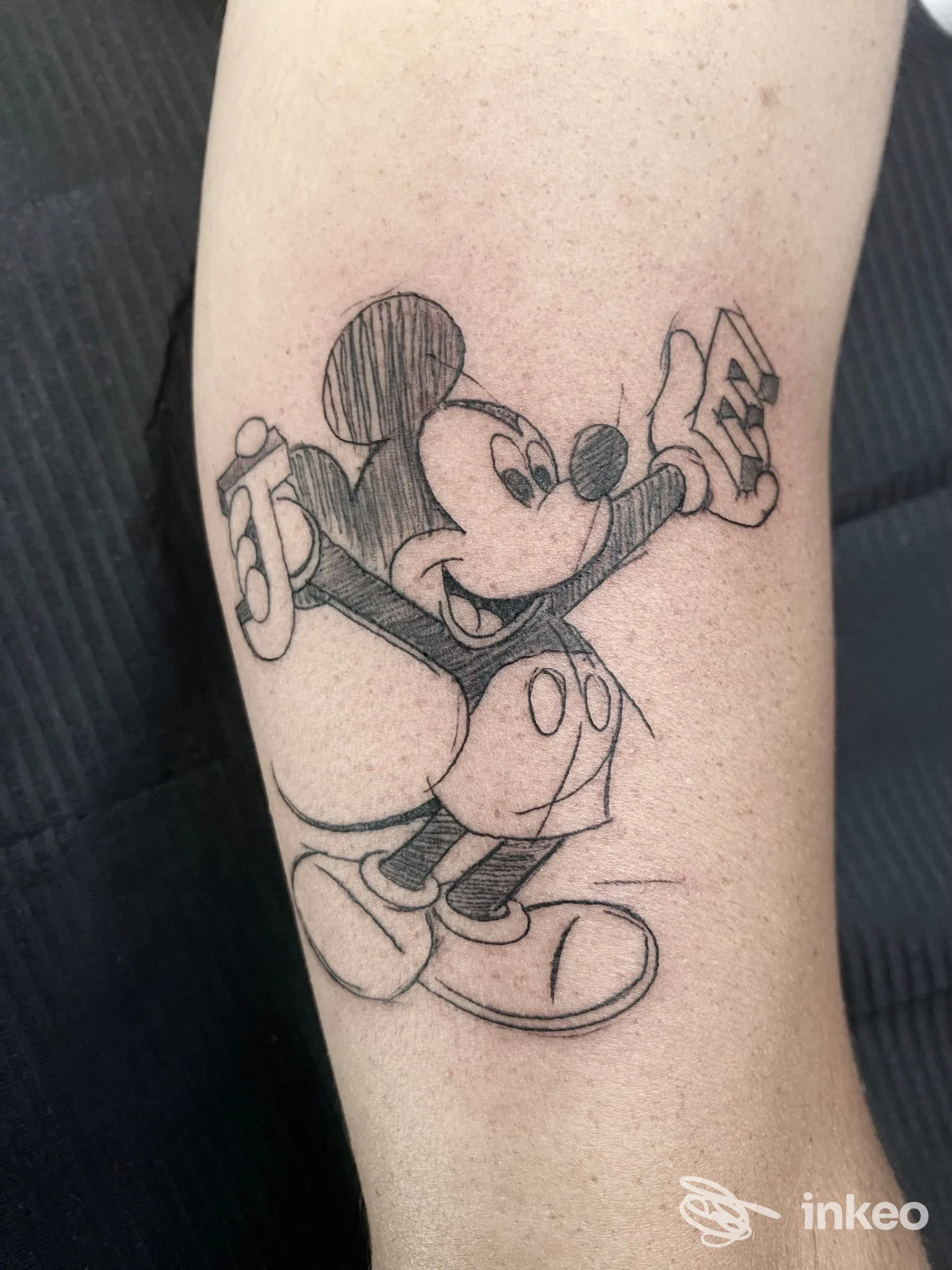 Tatuaggio a linee nere di un personaggio animato sull'avambraccio, fotografato nello studio Progressive Ink Tattoo a Dueville.