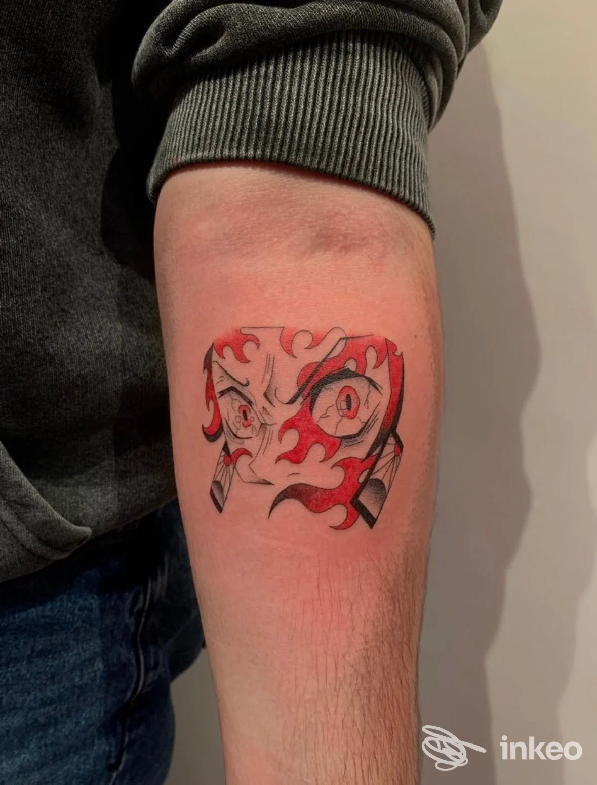 Tatuaggio sul avambraccio con volto stilizzato e fiamme rosse, foto fornita da Queen Of Ink Clinique Tattoo, Villa Fontana.