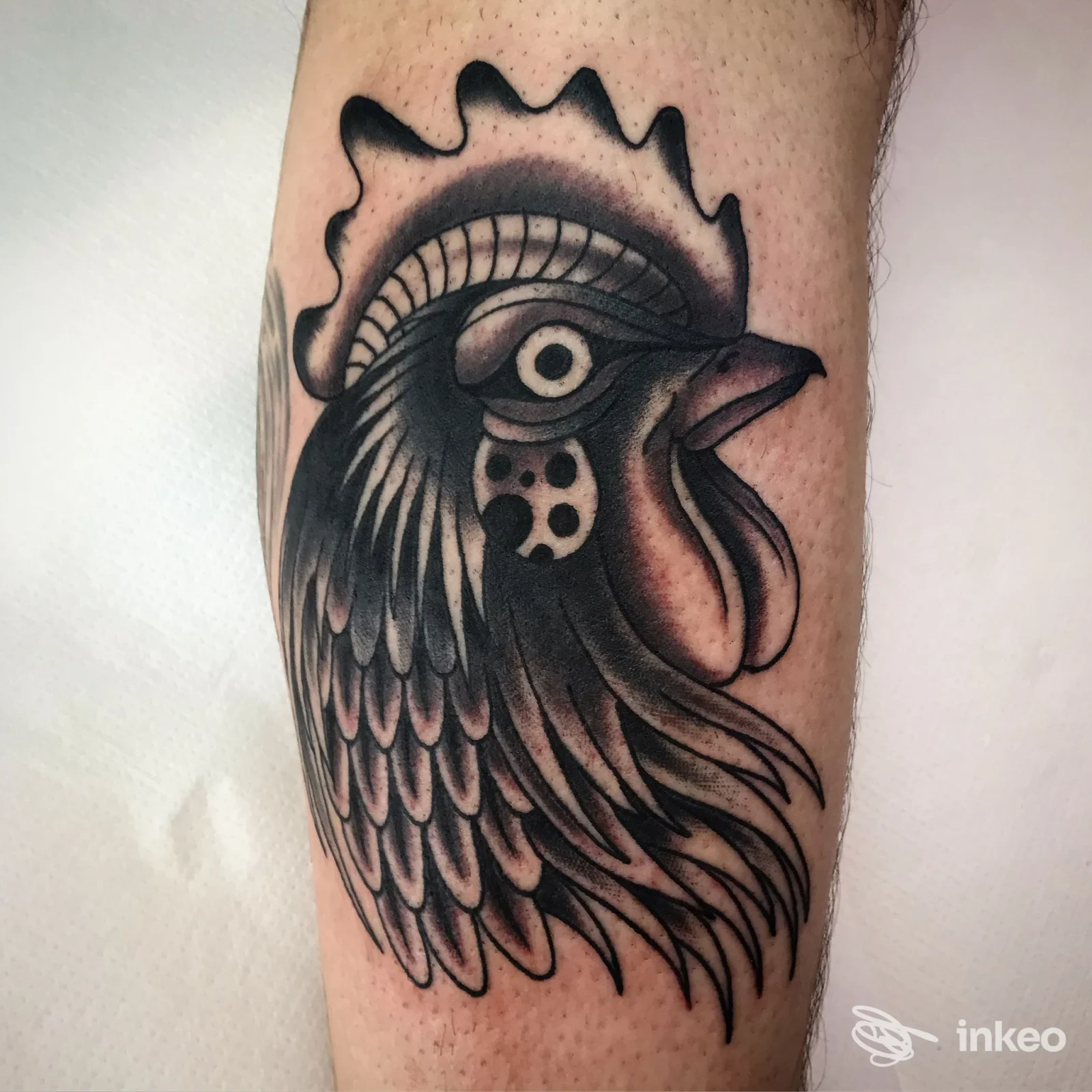 Primo piano di un tatuaggio testa di gallo in nero e grigio sull'avambraccio, realizzato da RED REAPER TATTOO a Fontane.