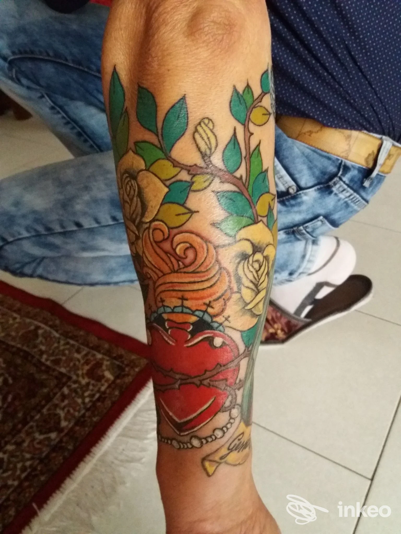 Avambraccio con tatuaggio colorato di rose e un cuore trafitto; immagine fornita dallo studio Raffaello Tattoo, Adria.