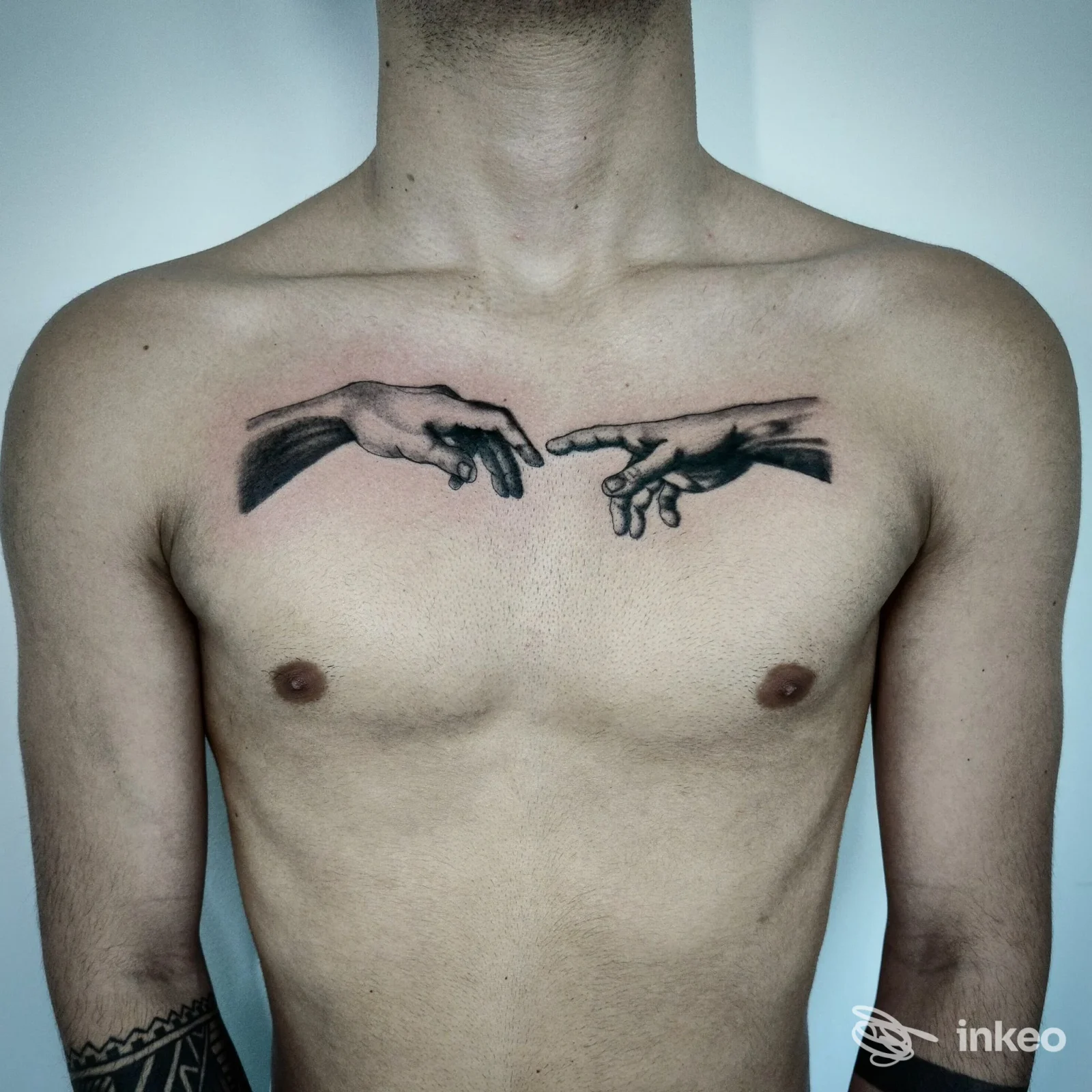 Tatuaggio a petto raffigurante due mani che si sfiorano, realizzato da Ruvoxa Tattoo a Treviso, fotografia frontale del torace.