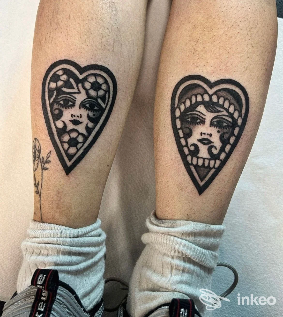 Due tatuaggi neri a cuore con volti stilizzati sui polpacci, foto fatta in studio; STIGMATA TATTOO, Castelfranco Veneto.