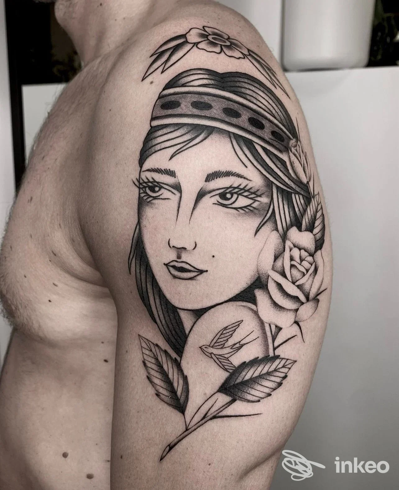Tatuaggio in bianco e nero sul braccio/spalla raffigurante il volto stilizzato di una donna con fiori — SUMISURA TATTOO STUDIO, Solesino.