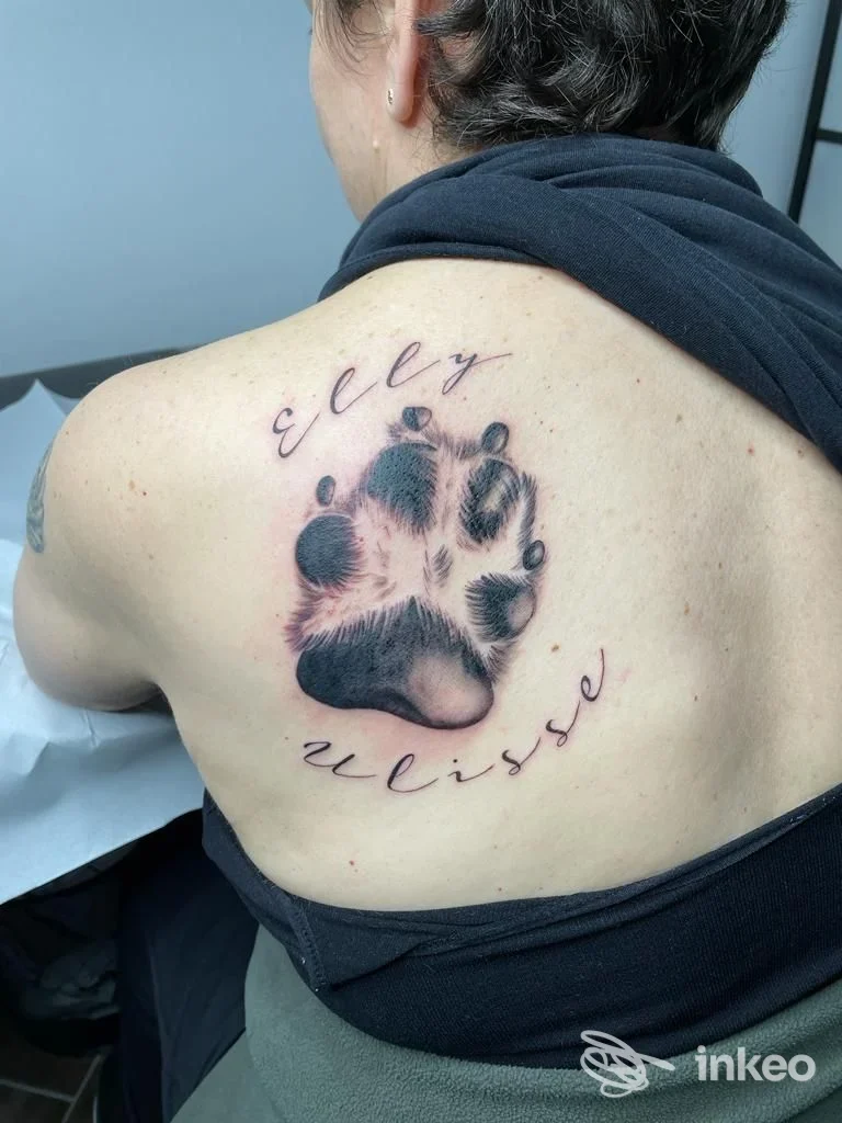 Tatuaggio a impronta di zampa con scritte sulla spalla sinistra, eseguito da Scolopender Tattoo a Camalò.