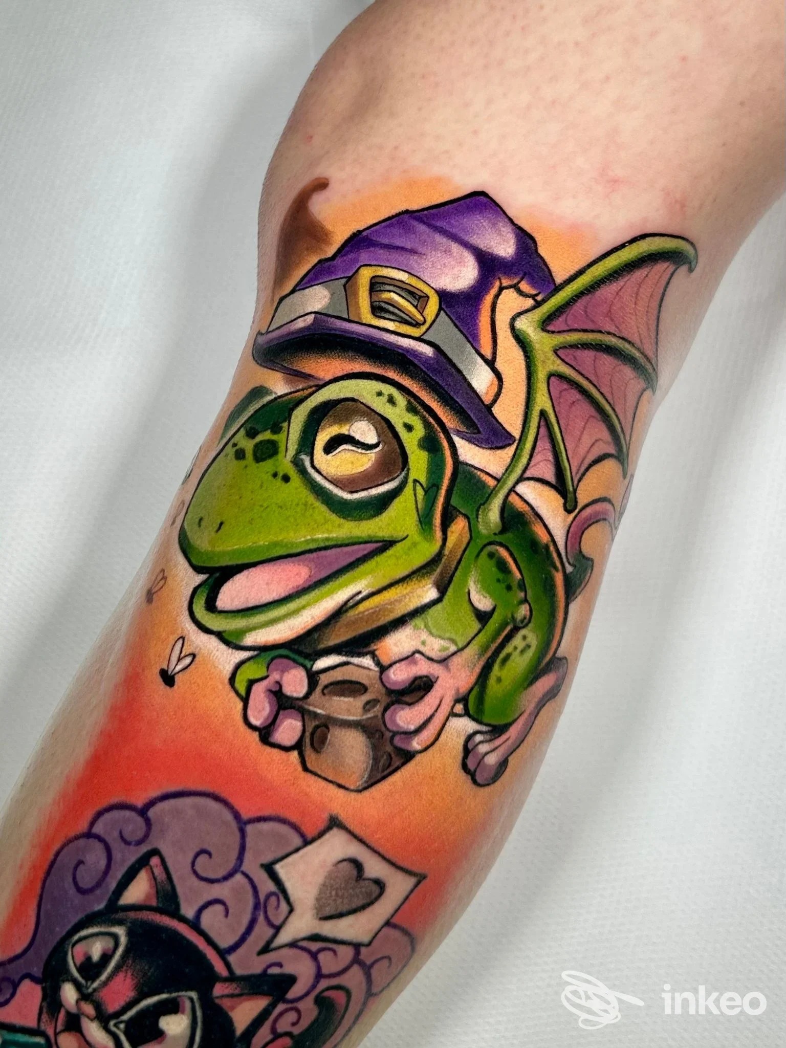 Tatuaggio colorato di una rana alata in stile cartoon sull'avambraccio, Senza tempo tattoo, Stra.