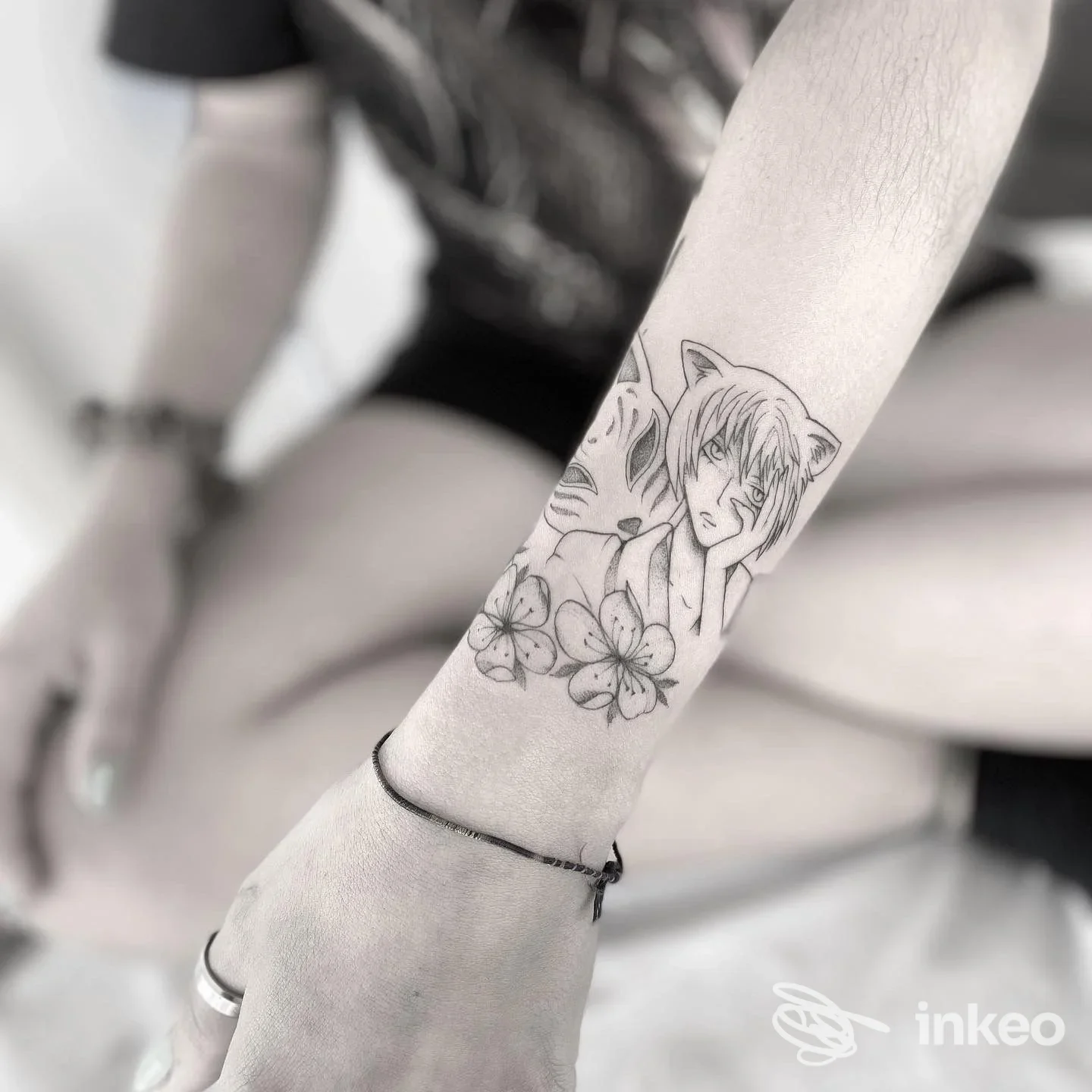 Avambraccio tatuato con un personaggio in stile anime e fiori, foto fornita da Shader Loopus Tattoo Studio a Bassano del Grappa.