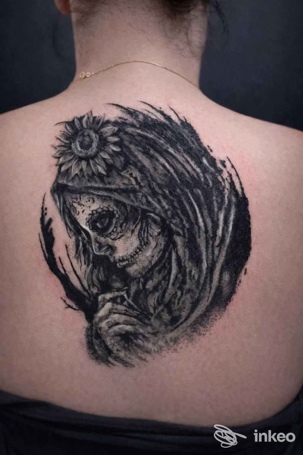Grande tatuaggio in bianco/nero di una figura scheletrica velata con girasole sulla parte superiore della schiena, foto fornita da Restart Tattoo, Verona.