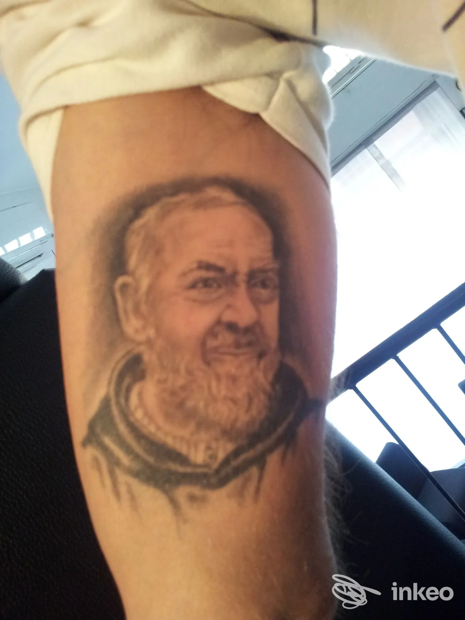 Tatuaggio realistico di un volto sul braccio, ritratto su pelle visibile senza elementi promozionali. Studio non indicato.