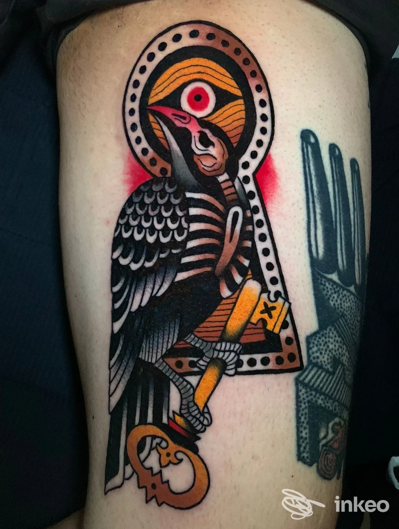 Tatuaggio neo-traditional di un uccello stilizzato sulla coscia, con neri, gialli e rosso, fotografato da Skingdom Tattoo, Volpago del Montello.