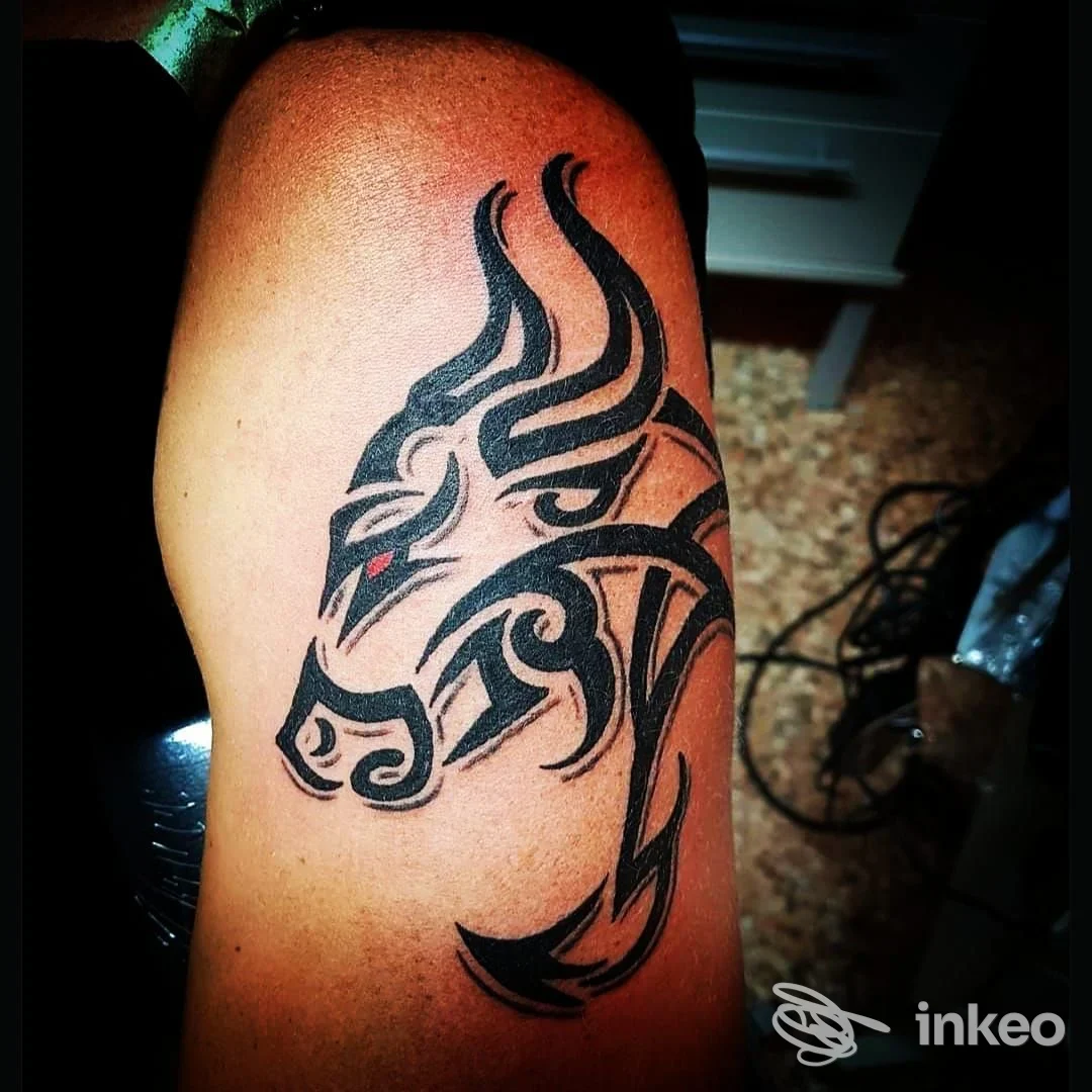 Tatuaggio tribale a inchiostro nero raffigurante testa animale sul braccio superiore, Wanted Tattoo, Schio.