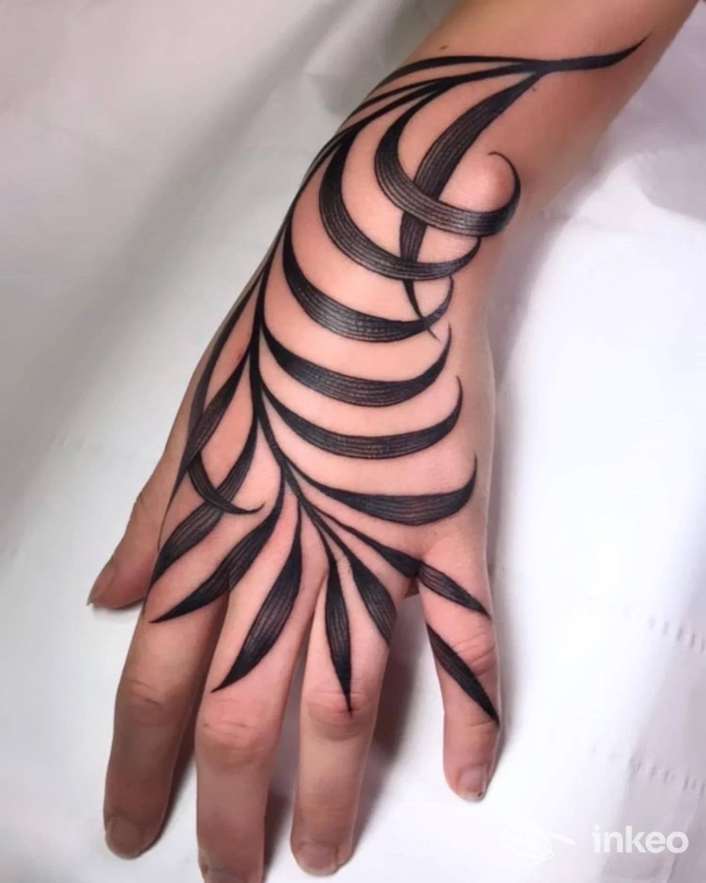 Dettaglio di qualità di un tatuaggio ornamentale nero che copre il dorso e le dita di una mano. Scatto di Twin Flame tattoo lab a Rubano.