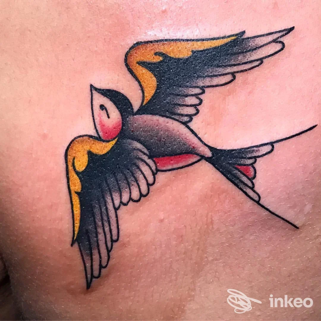 Tatuaggio tradizionale di rondine colorata sul petto, eseguito da Z-Ink Tattoo a Grisignano di Zocco.