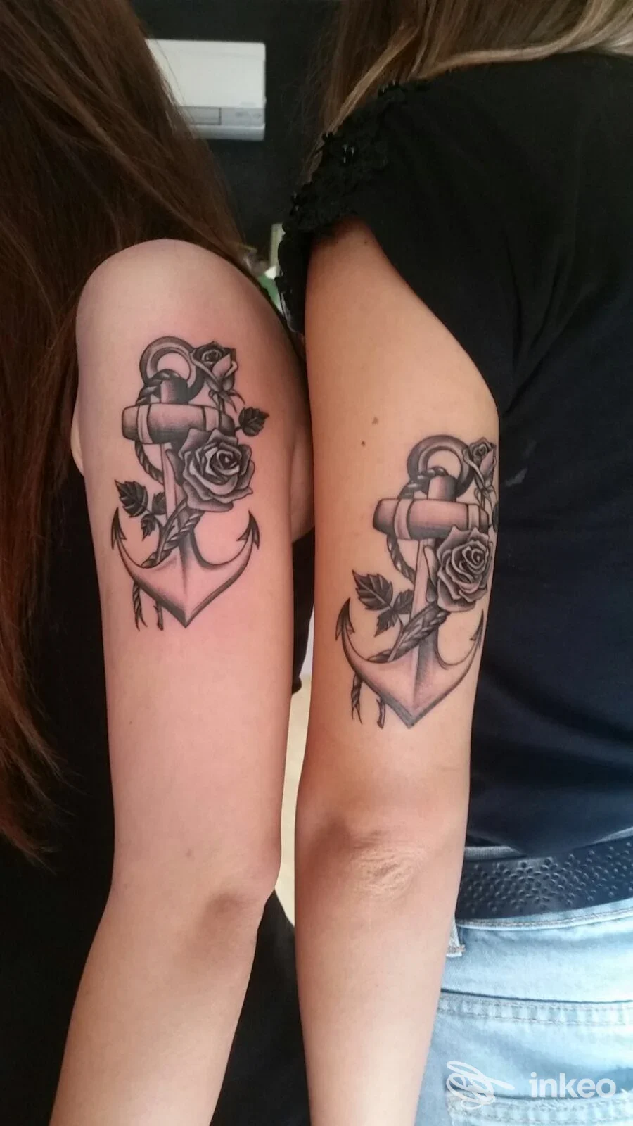 Due braccia con tatuaggi abbinati ancora e rosa in bianco e nero, scatto sul bicipite superiore. Armonia Tattoo, San Zeno.