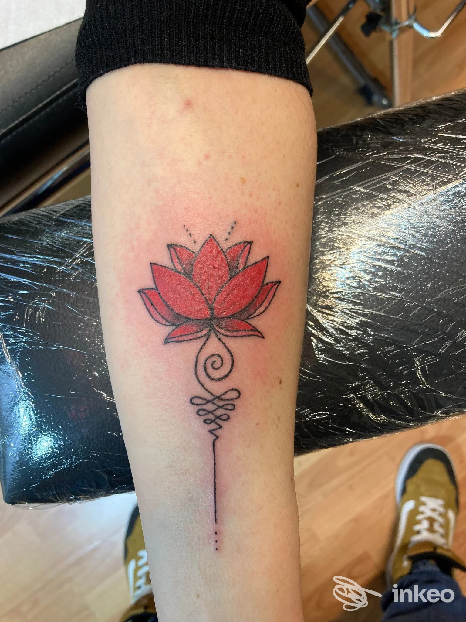 Tatuaggio a loto rosso con elementi lineari sull'avambraccio, realizzato presso Black Jack tattoo studio a Verona.