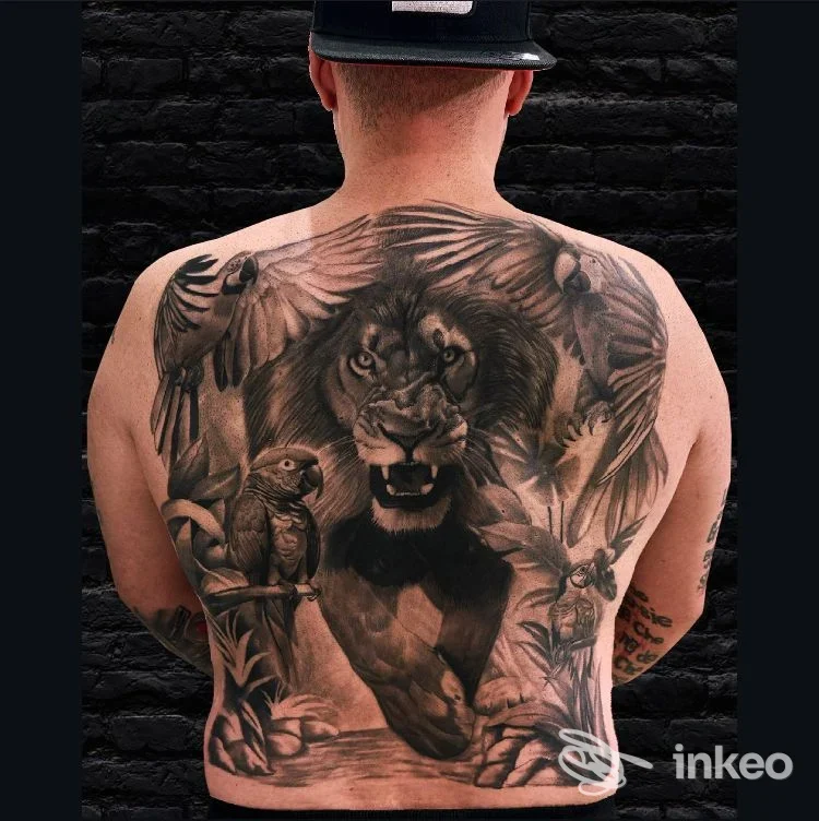 Grande tatuaggio sulla schiena con leone realistico e uccelli, foto di Black Wire Tattoo a Mirano che mostra un backpiece completo.