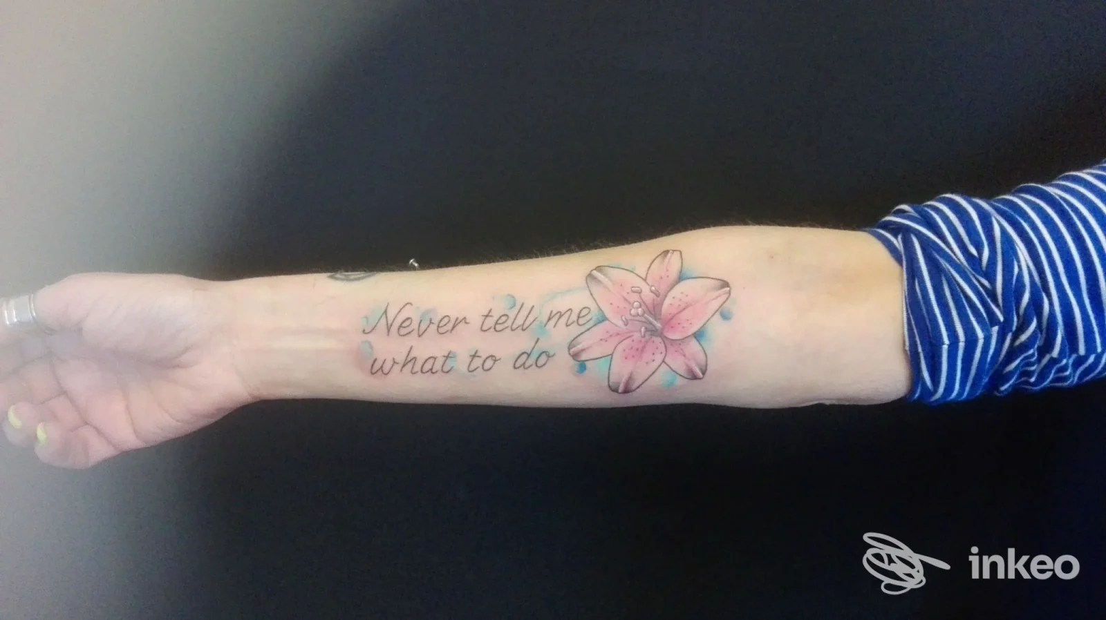Avambraccio con tatuaggio testuale 'Never tell me what to do' e giglio rosa, lavoro eseguito da Billion Dollar Tattoo, Candiana.