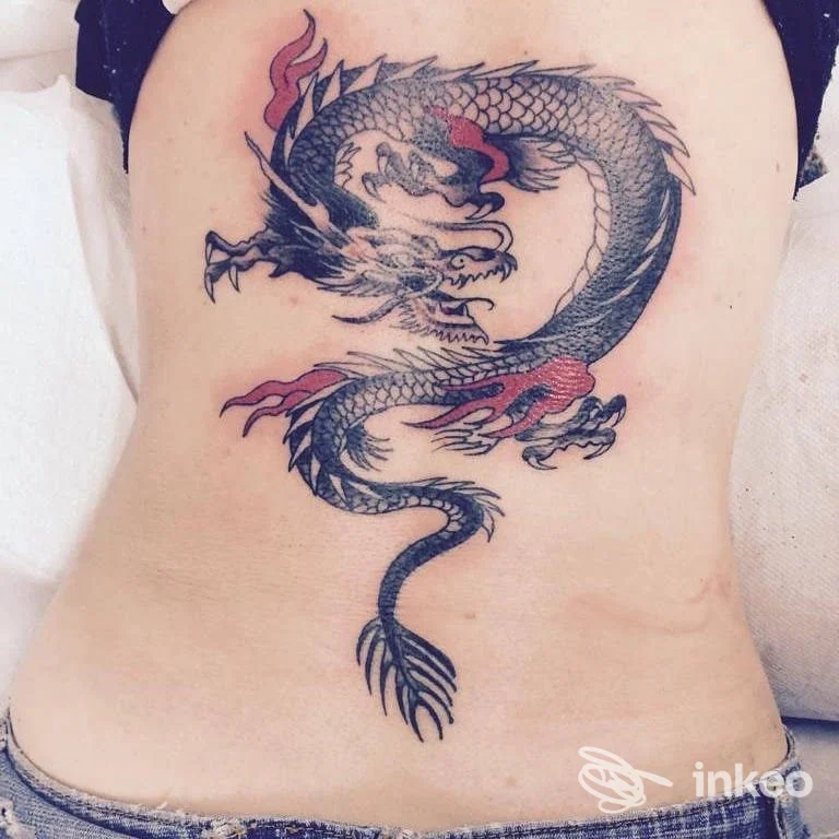 Grande tatuaggio a forma di drago nero e rosso sul fianco/bassa schiena, fotografato per Blackbell Tattoo Studio a Teolo.